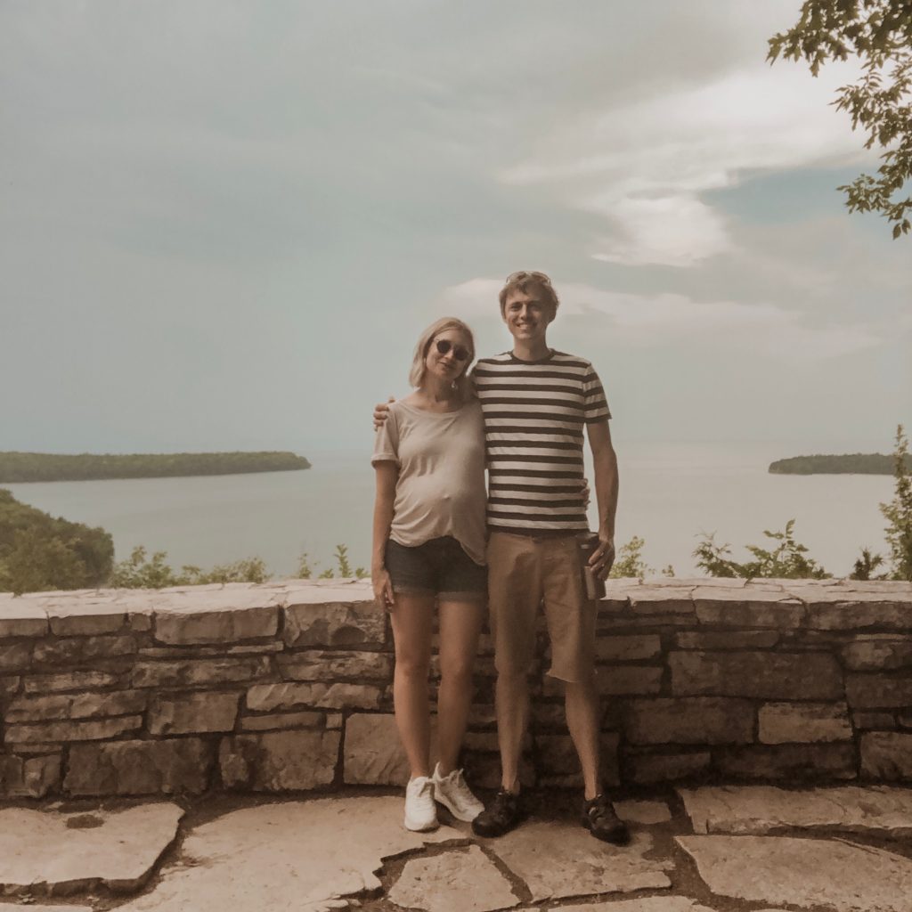 taking a selfie at peninsula state park in door county wisconsin, everlane striped men's tee, men's keen sandals, maternity outfit, maternity shorts, everlane tread sneakers