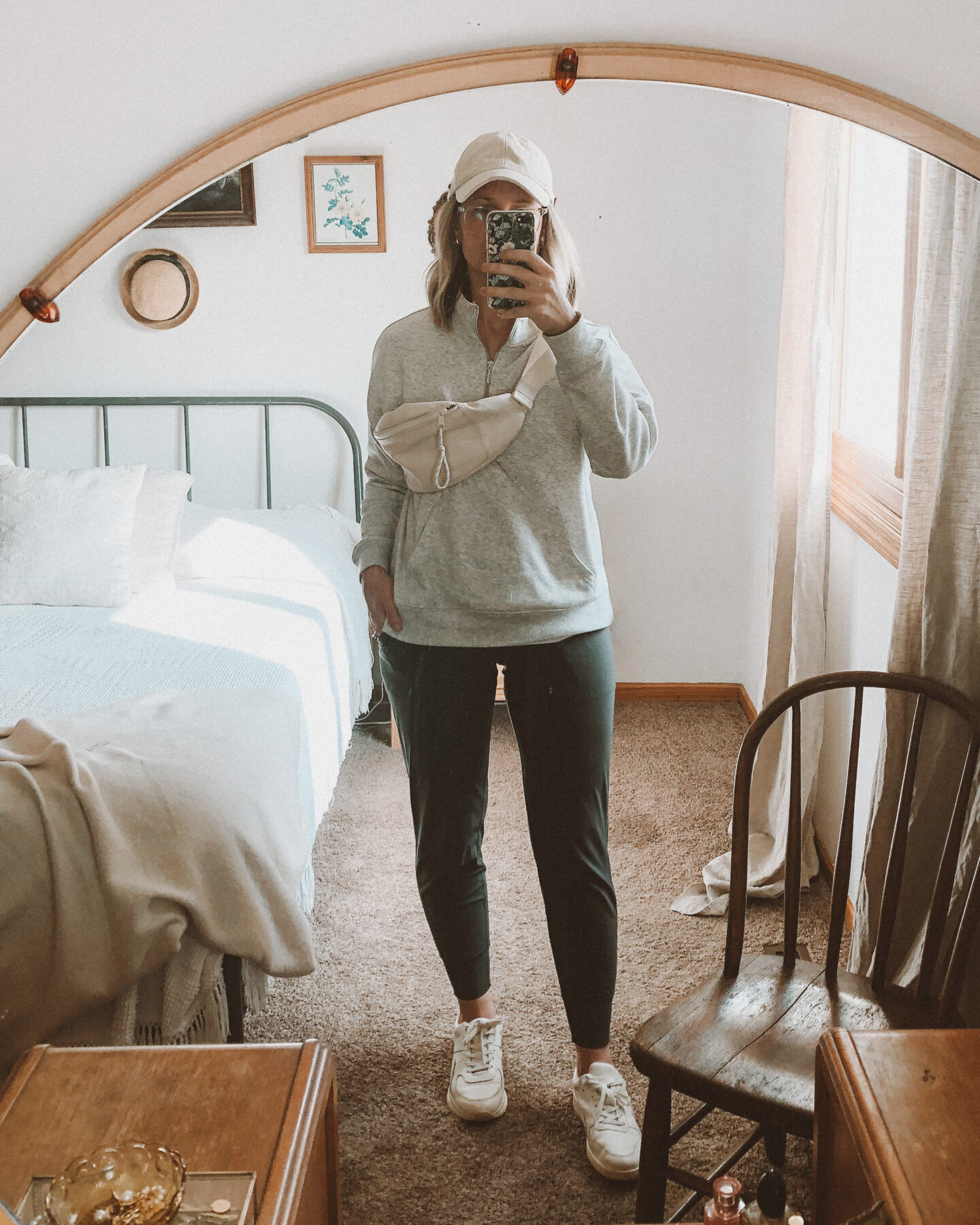 Fall Transitional Dressing: old navy gray zip up sweatshirt paired with a pair of their legging joggers plus everlane tread sneakers, a cream colored hip pack or fanny pack and a cream baseball hat