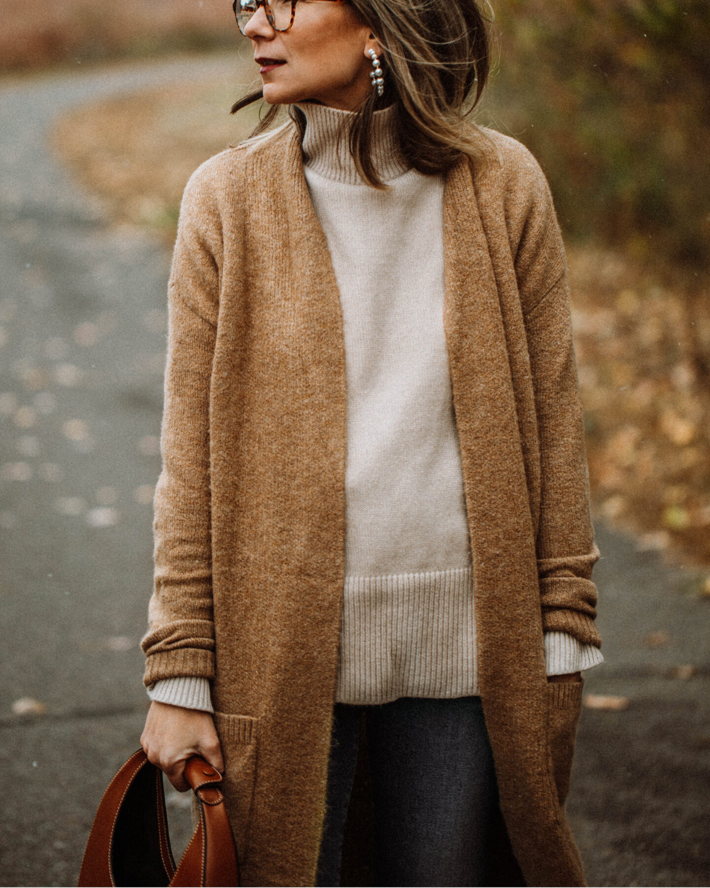 3 Cozy Outfits for Thanksgiving, camel duster maxi cardigan, taupe turtleneck sweater, blue skinny jeans, brownknee high croc effect boots, staud moon bag