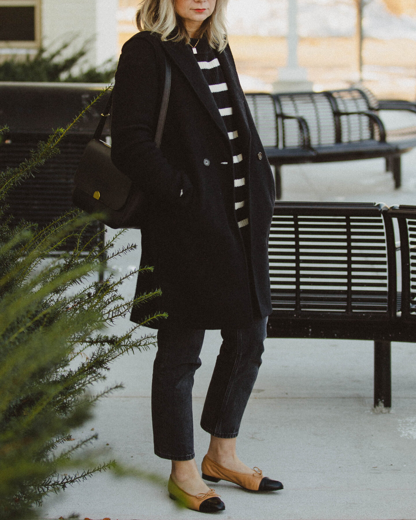 karin emily style. classic stripes, breton stripe sweater, j. crew wool coat, everlane 90's cheeky jean, washed black jeans, cap toe flats, black madewell bag, monogram necklace, oversized black sunglasses, blonde hair with bangs