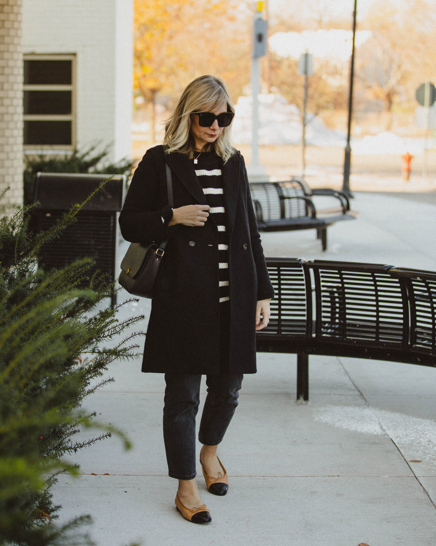 karin emily style. classic stripes, breton stripe sweater, j. crew wool coat, everlane 90's cheeky jean, washed black jeans, cap toe flats, black madewell bag, monogram necklace, oversized black sunglasses, blonde hair with bangs