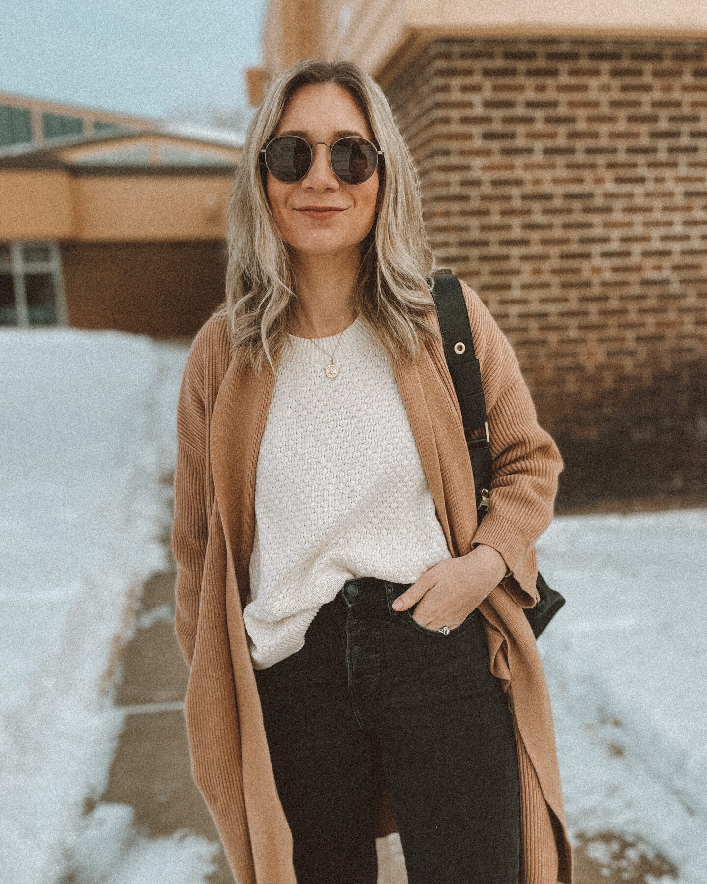 cream sweater, black leather back pack, gray skinny jeans, cream sweater