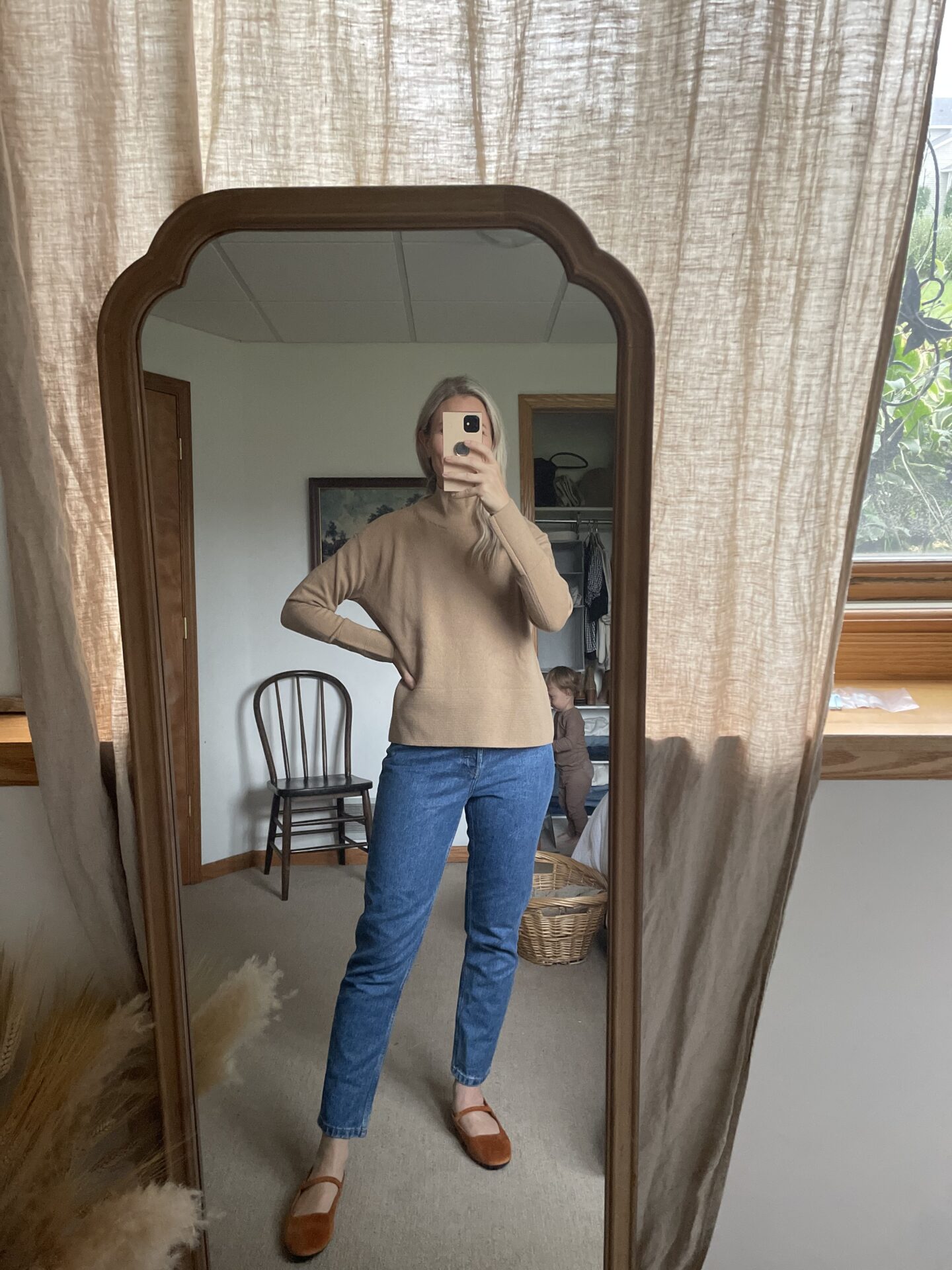 Karin Emily wears a cashmere camel colored turtleneck from Everlane 