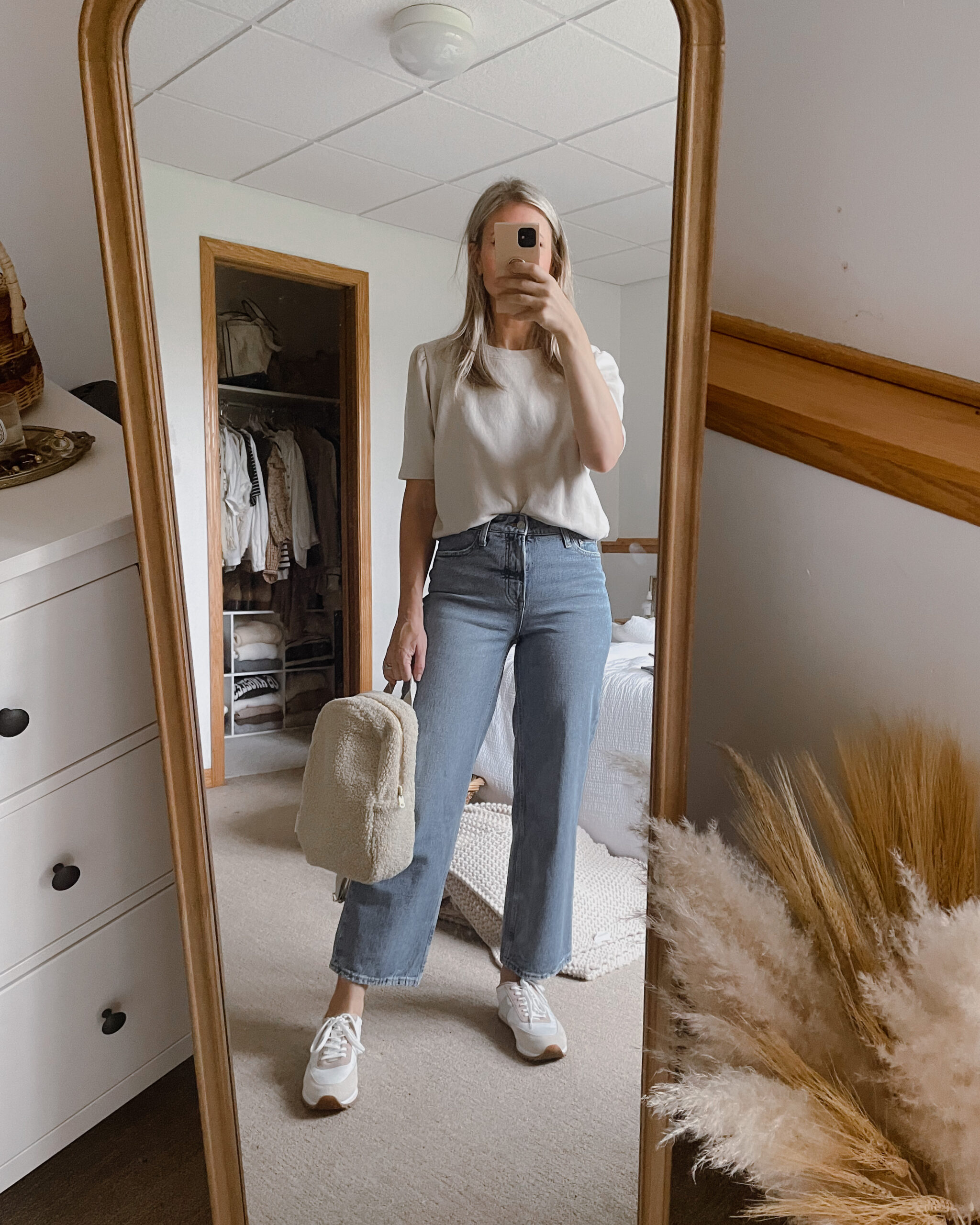 Karin Emily wears a puff sleeve sweatshirt from it is well L.A., a pair of wide leg jeans from Walmart, a sherpa backpack from studio noos, and a pair of J. Crew Sneakers