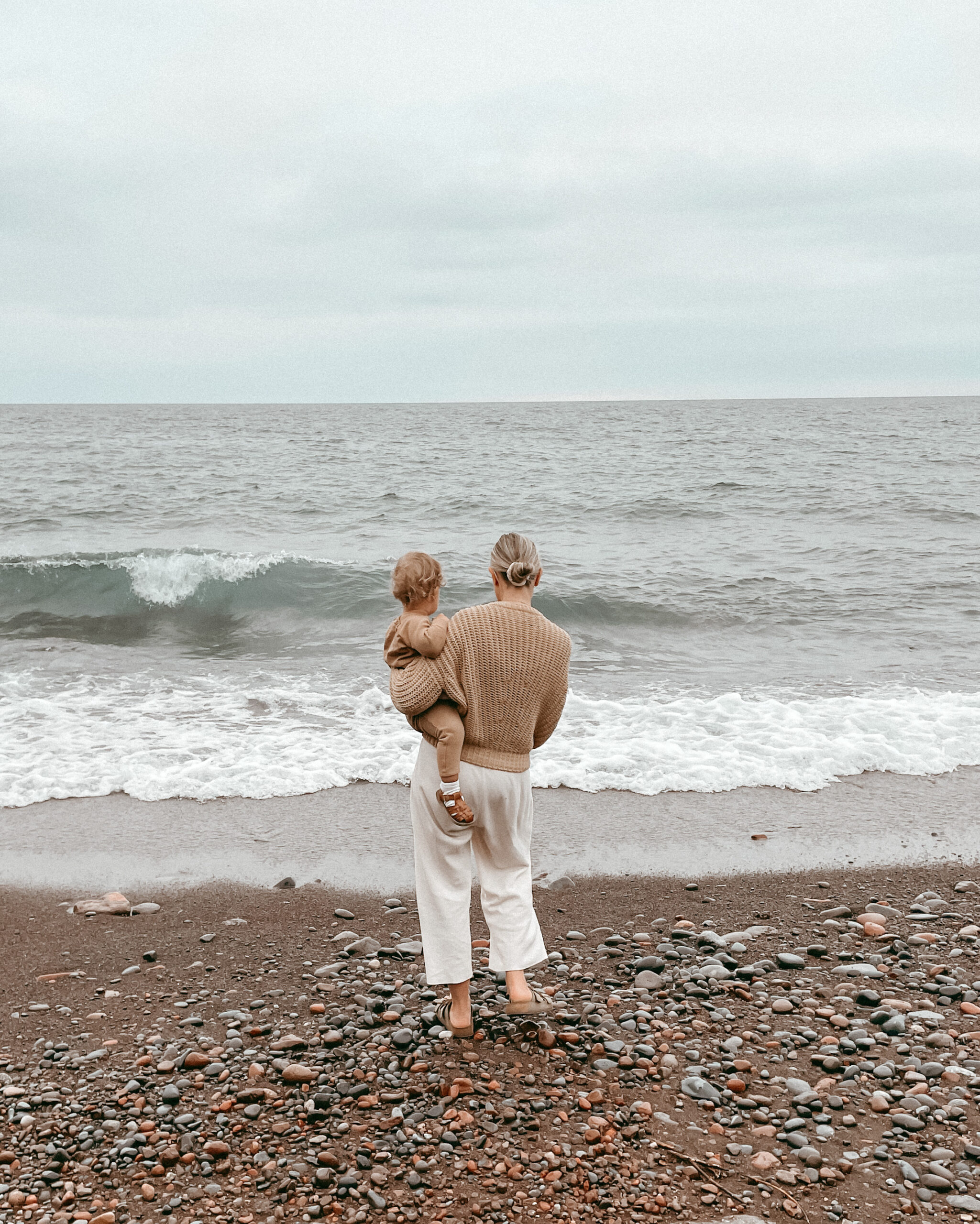 karin emily standing on the beach wearing the babaa jumper no 18 in clay pot and a pair of waffle knit mate the label wide leg louneg pants