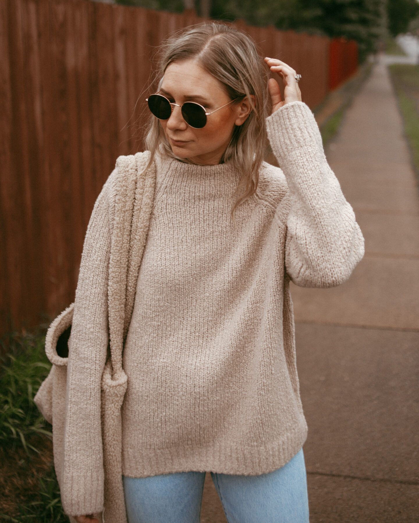 Karin Emily wearing an oversized cozy sweater for fall and a pair of light wash levi's with a studio noos sherpa bag