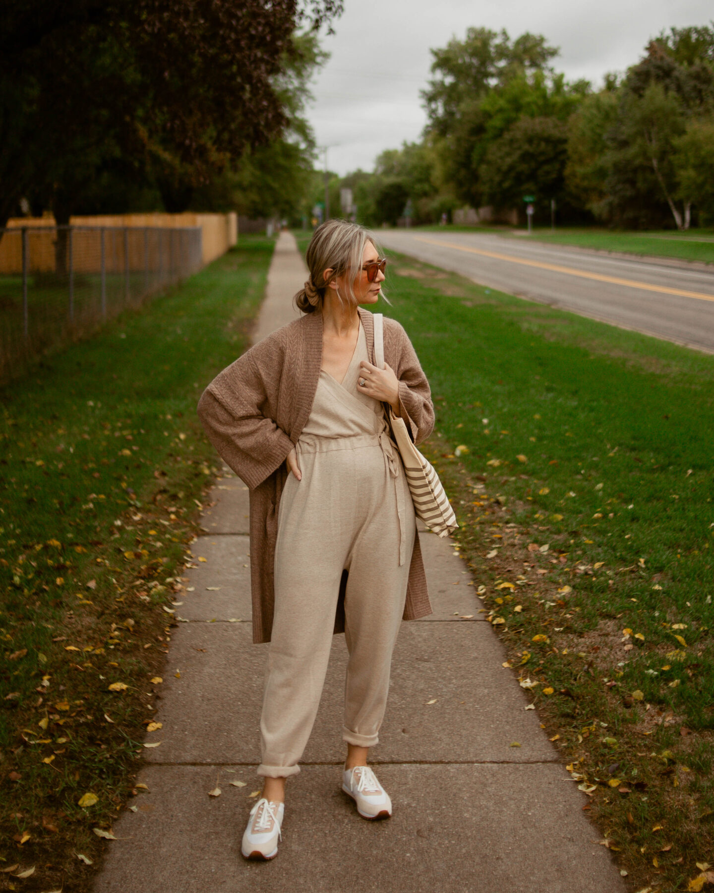 Karin Emily Wears a merino wool jumpsuit and oversized camel cardigan with a pair of sneakers and striped reusable tote bag all from J. Crew