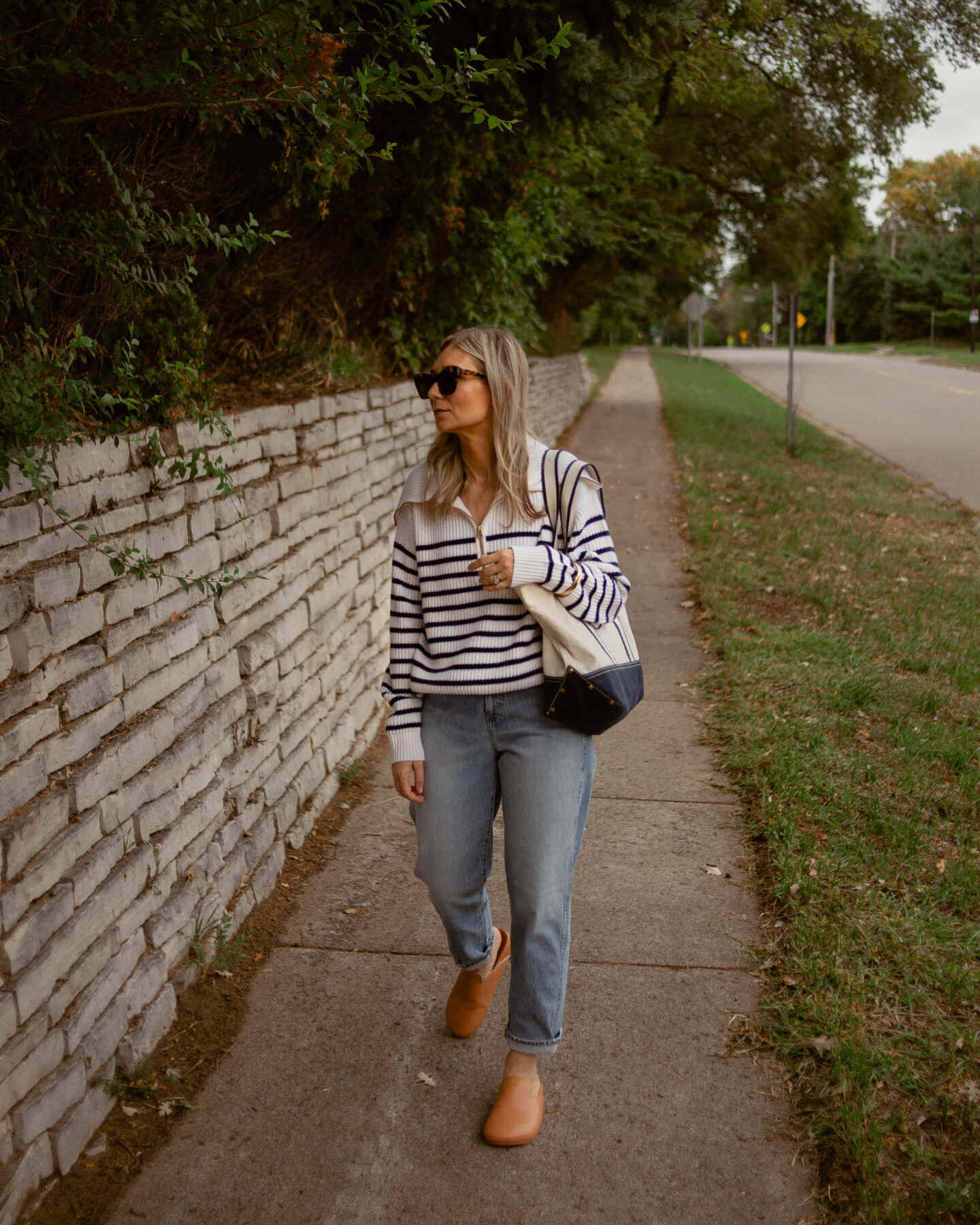 Karin Emily Wears a cashmere breton stripe sweater, light wash relaxed jeans, and sherpa mules - all from J. Crew