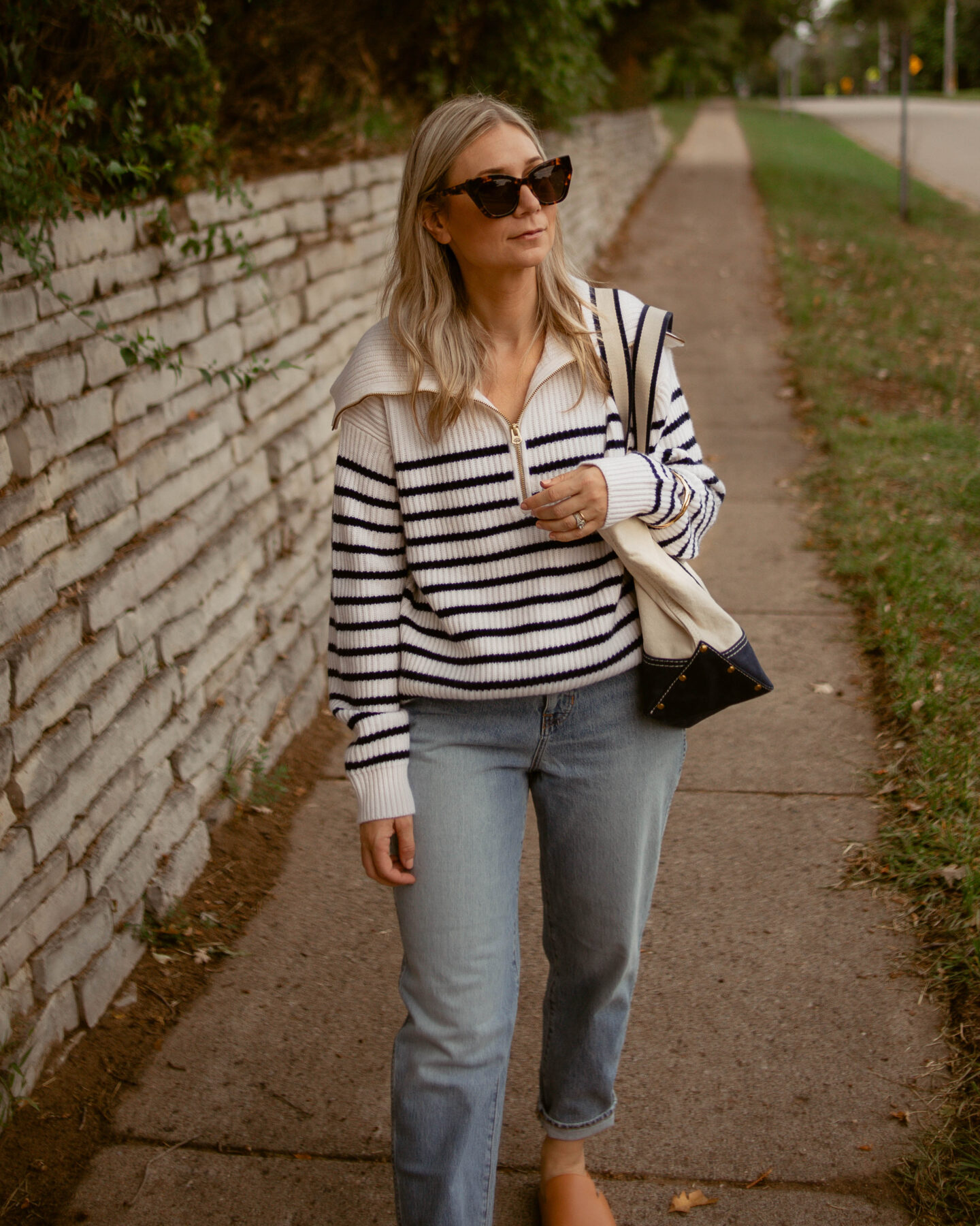 Karin Emily Wears a cashmere breton stripe sweater, light wash relaxed jeans, and sherpa mules - all from J. Crew