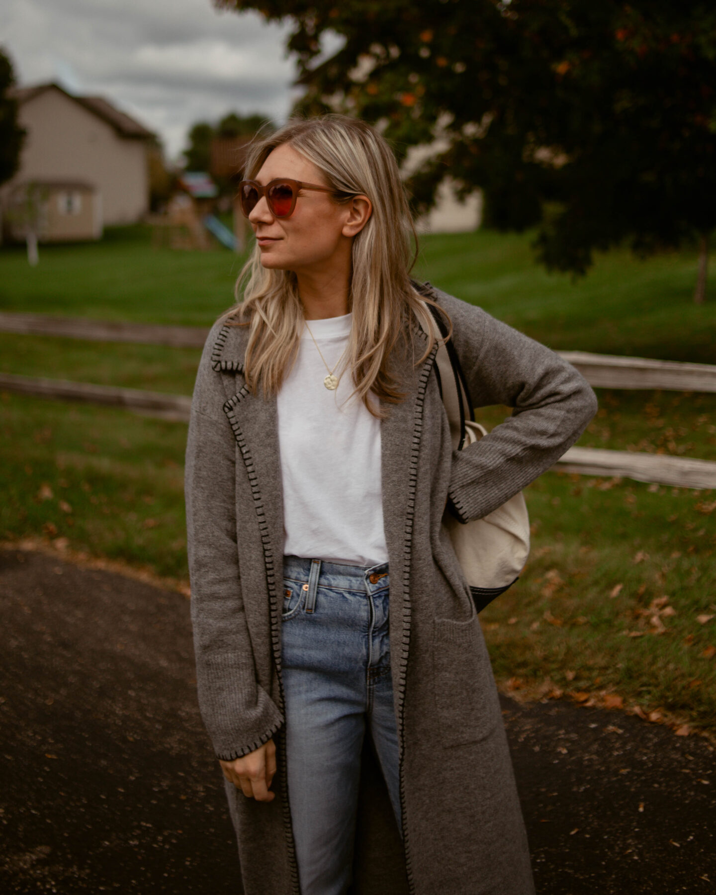 Karin Emily wears a relaxed pair of jeans and an oversized white tee under a gray maxi cardigan