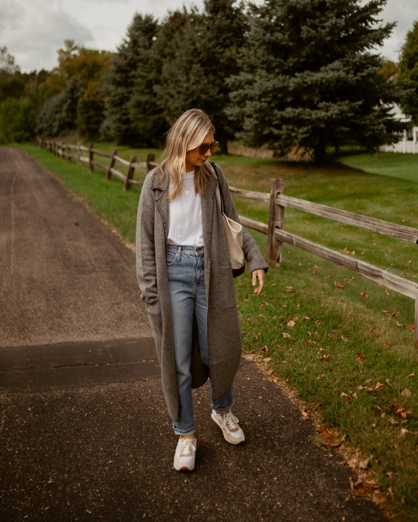 Karin Emily wears a relaxed pair of jeans and an oversized white tee under a gray maxi cardigan