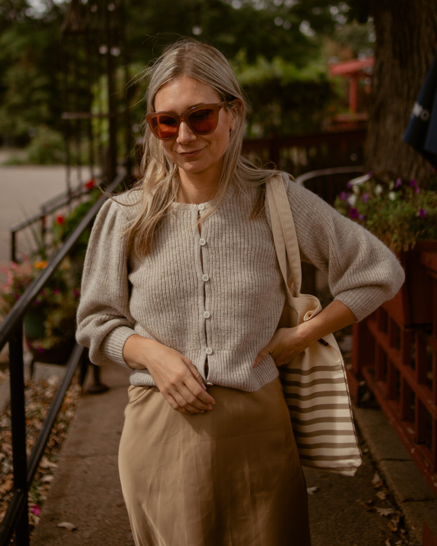 Karin Emily wears a comfy and chic fall outfit: a puff sleeve cardigan with a camel colored slip skirt and a pair of tennis shoes