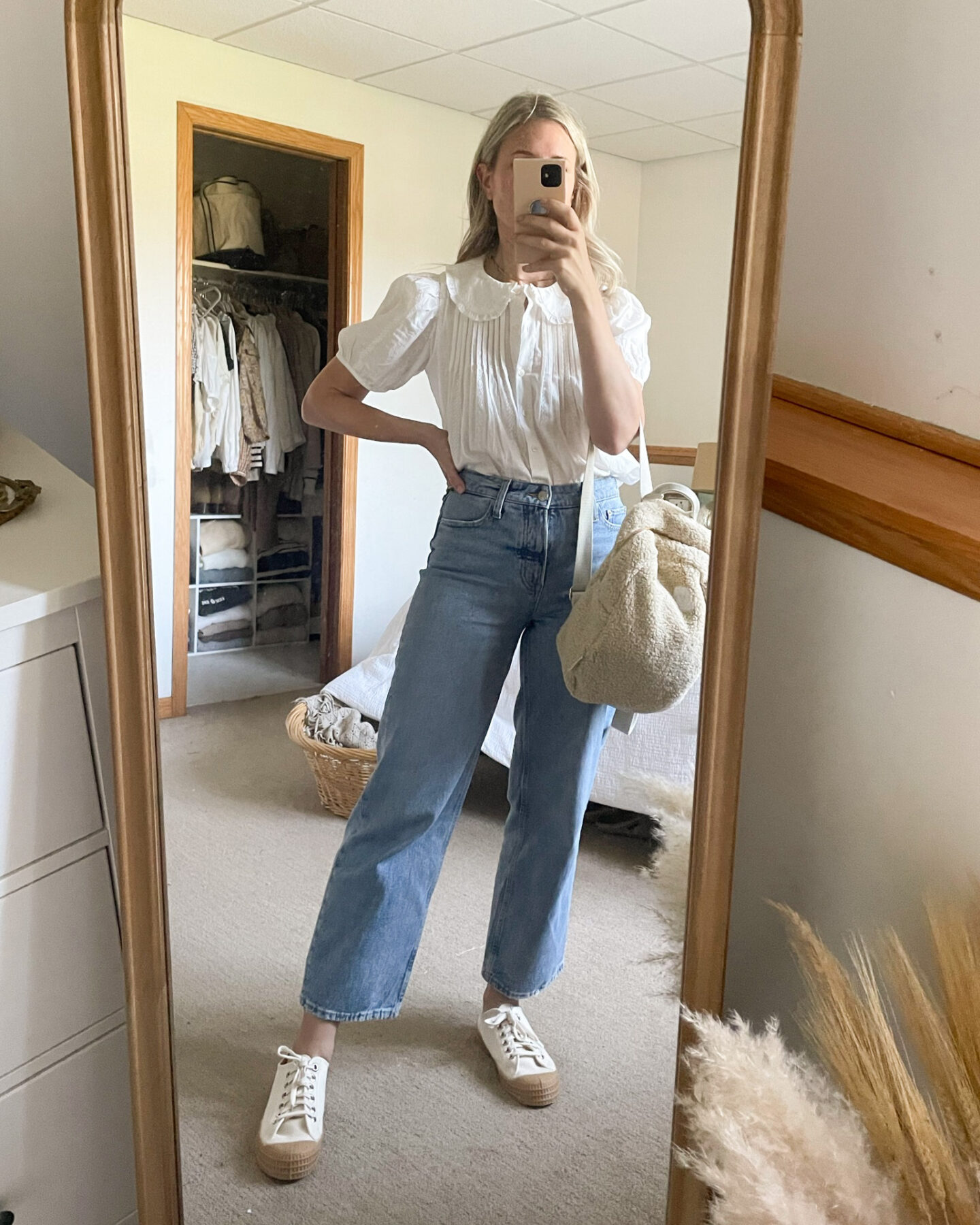 Karin Emily wears a puff sleeve blouse tucked into wide leg jeans with a sherpa backpack and canvas sneakers