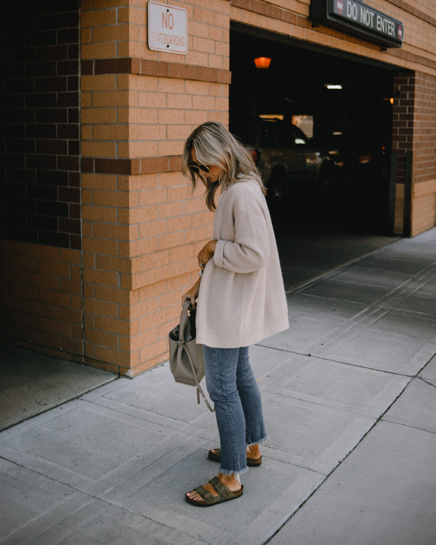 karin emily wearing the jenni kayne cashmere cocoon cardigan with a cream tee and madewell perfect vintage jeans, a pair of birkenstock arizonas, and a pair of clear sunglasses