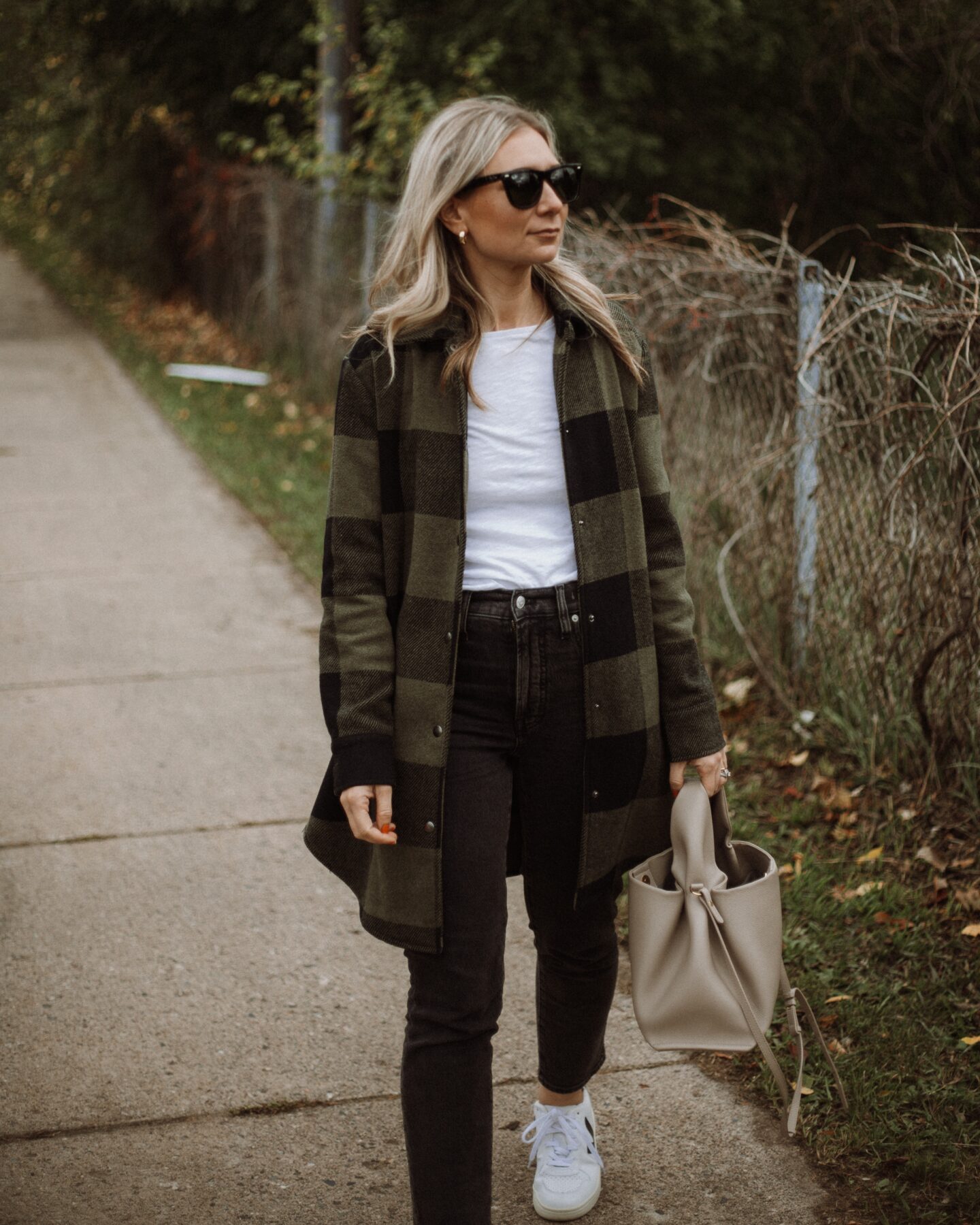 Karin Emily wears a white tee, plaid shacket, washed black perfect vintage jeans from Madewell and Veja V-10 Sneakers