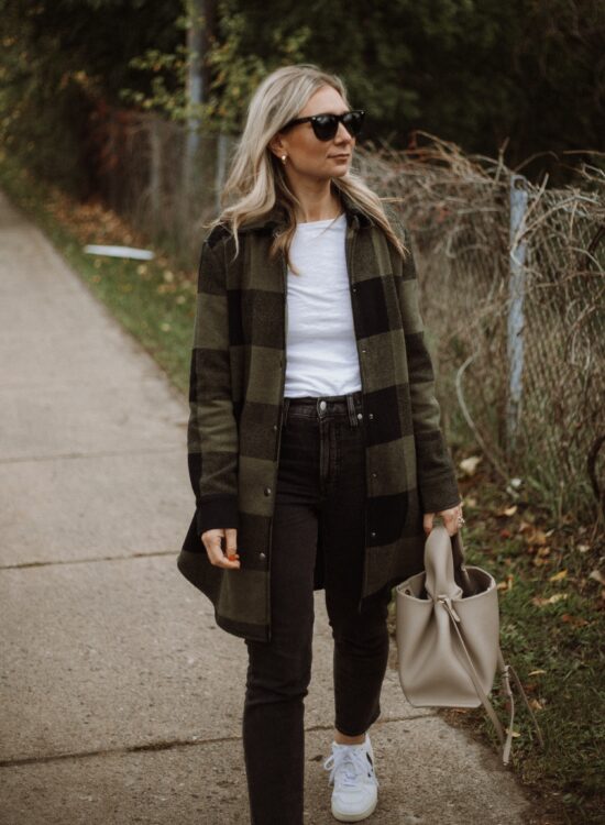 Karin Emily wears a white tee, plaid shacket, washed black perfect vintage jeans from Madewell and Veja V-10 Sneakers