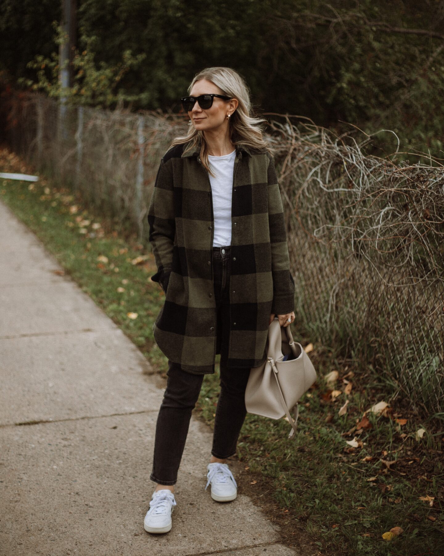 Karin Emily wears a white tee, plaid shacket, washed black perfect vintage jeans from Madewell and Veja V-10 Sneakers