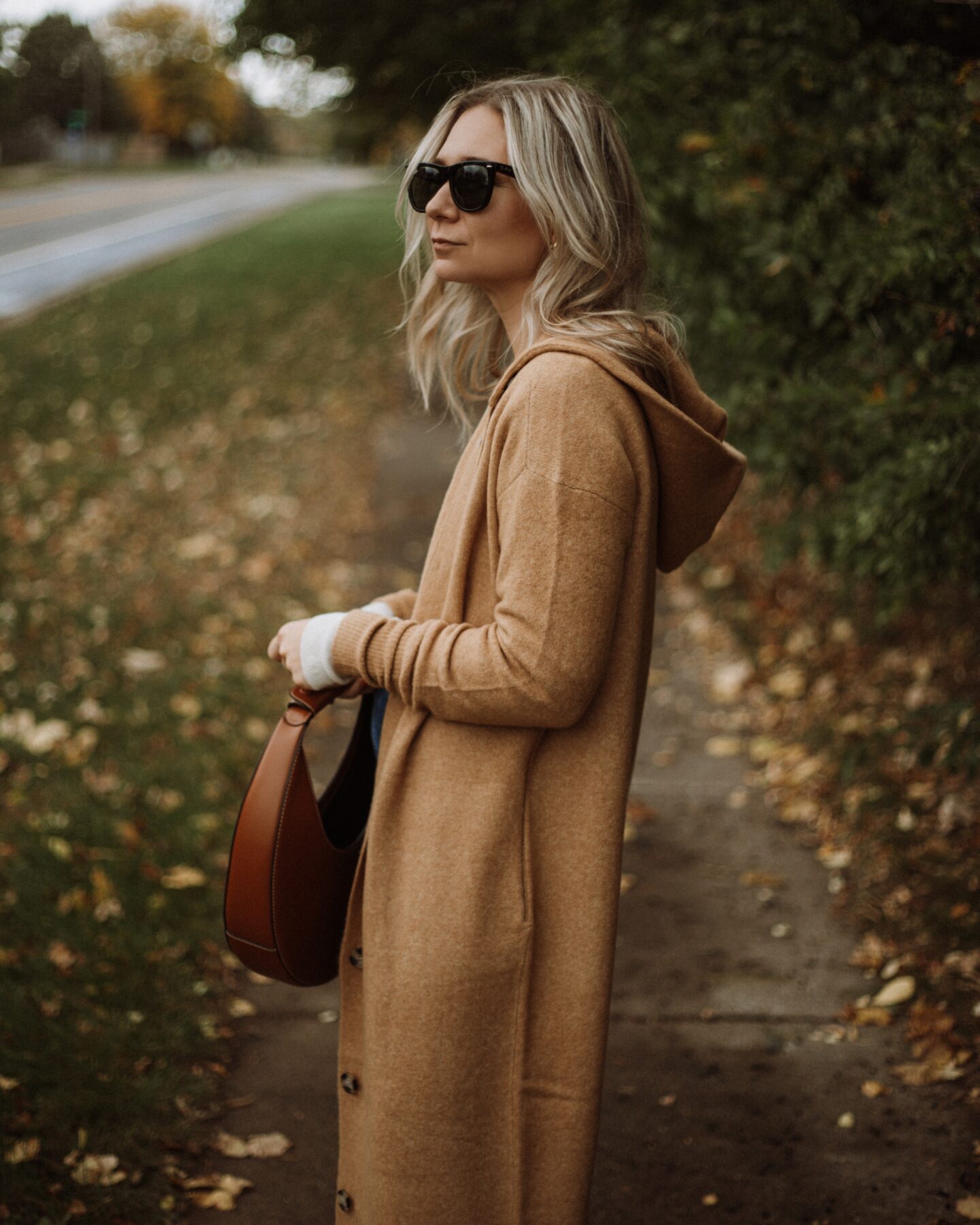 Karin Emily wears a long maxi cardigan from Everlane, a henley tee, and a staud moon bag