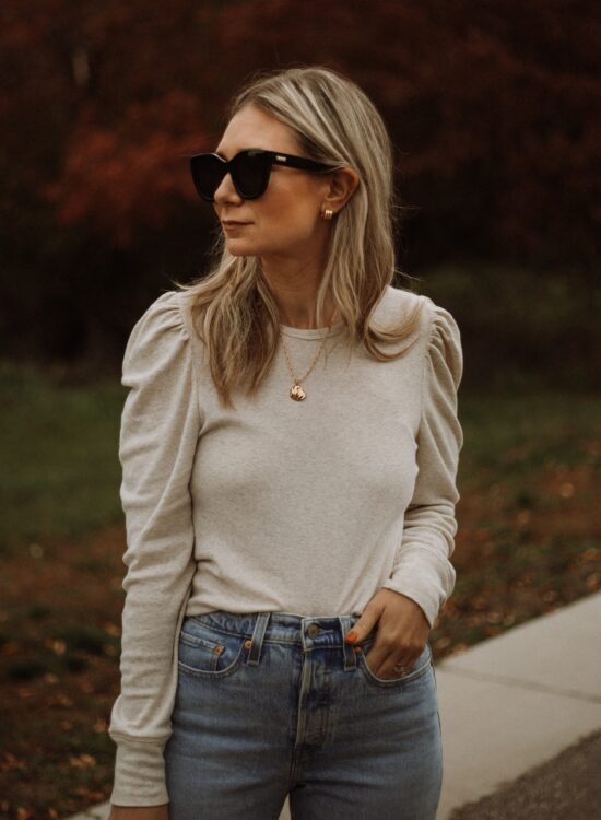 Karin Emily wear a puff sleeve top, light wash wedgie icon Levi jeans and le specs black air heart sunglasses