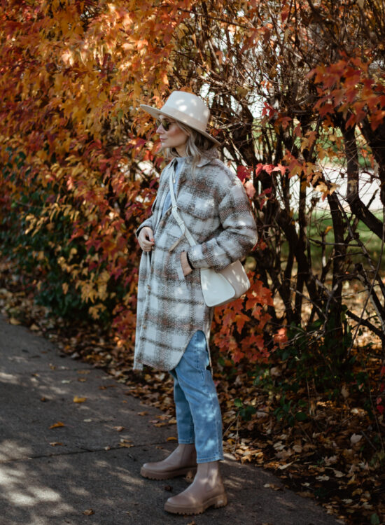 Karin Emily wears a plaid shacket, light wash jeans, a cream hat, and tan lug boots