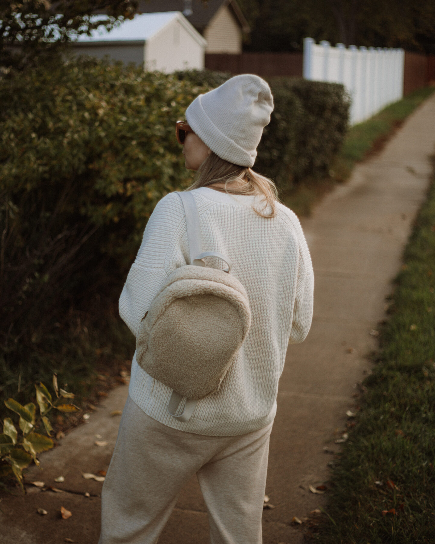 Karin Emily wears the Tradlands Shelter Cardigan, a J Crew Wool Jumpsuit and Sneakers and a Sherpa Backpack