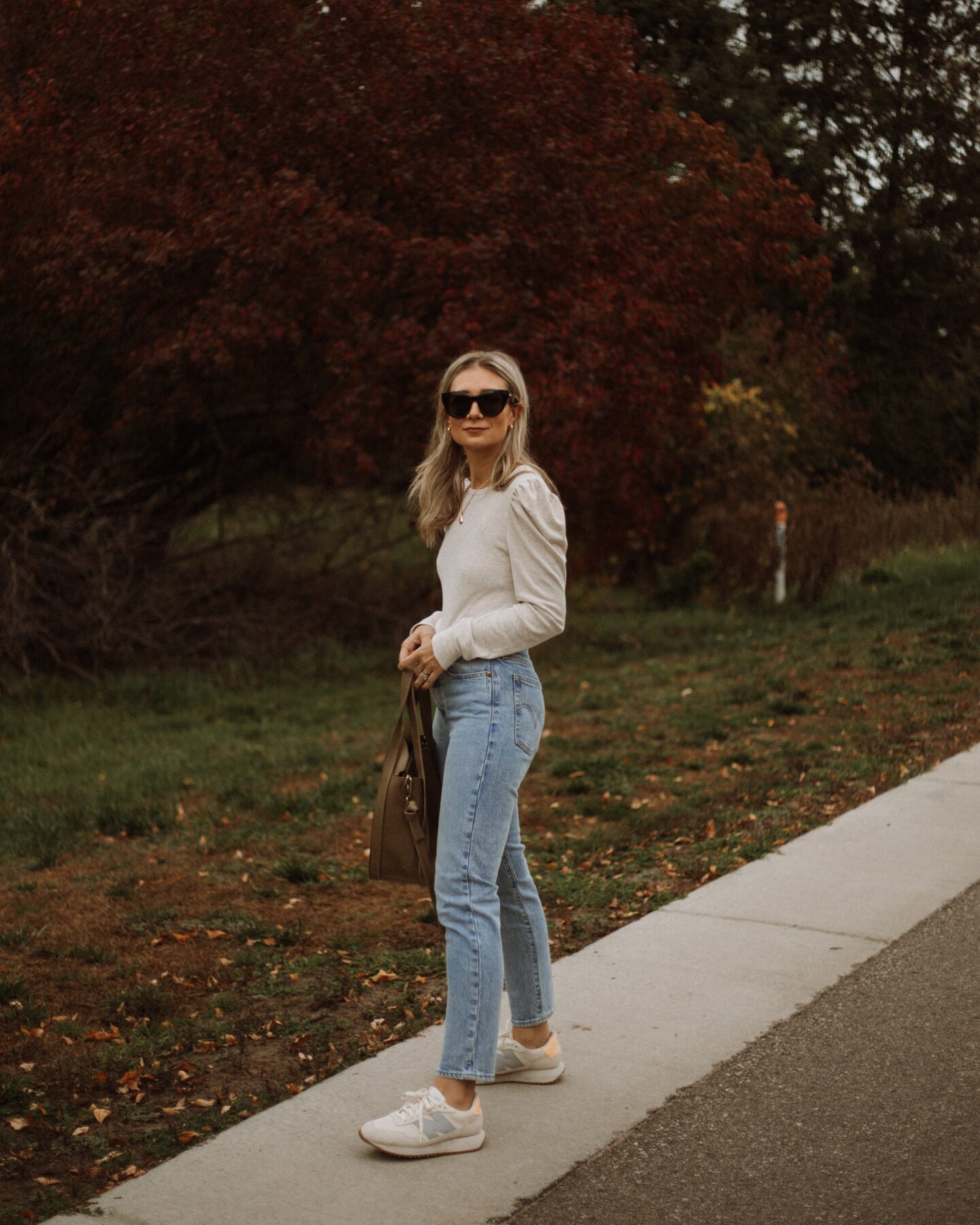 Karin Emily wear a puff sleeve top, light wash wedgie icon Levi jeans, new balance sneakers, and le specs black air heart sunglasses