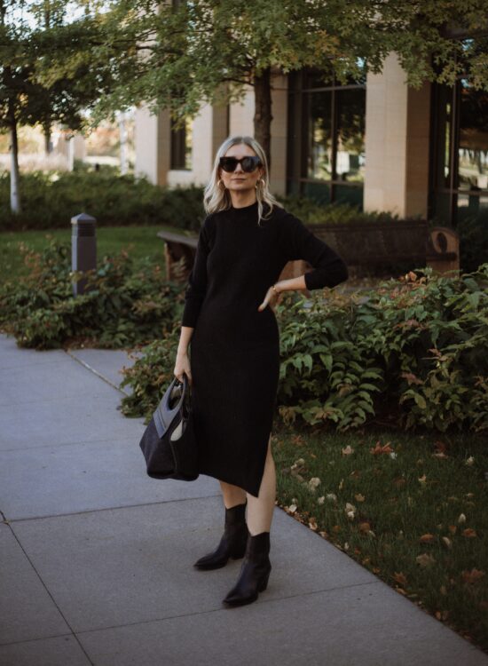 Karin Emily wears a black sweater dress, hereu bag, black cowboy boots, and oversized black sunglasses