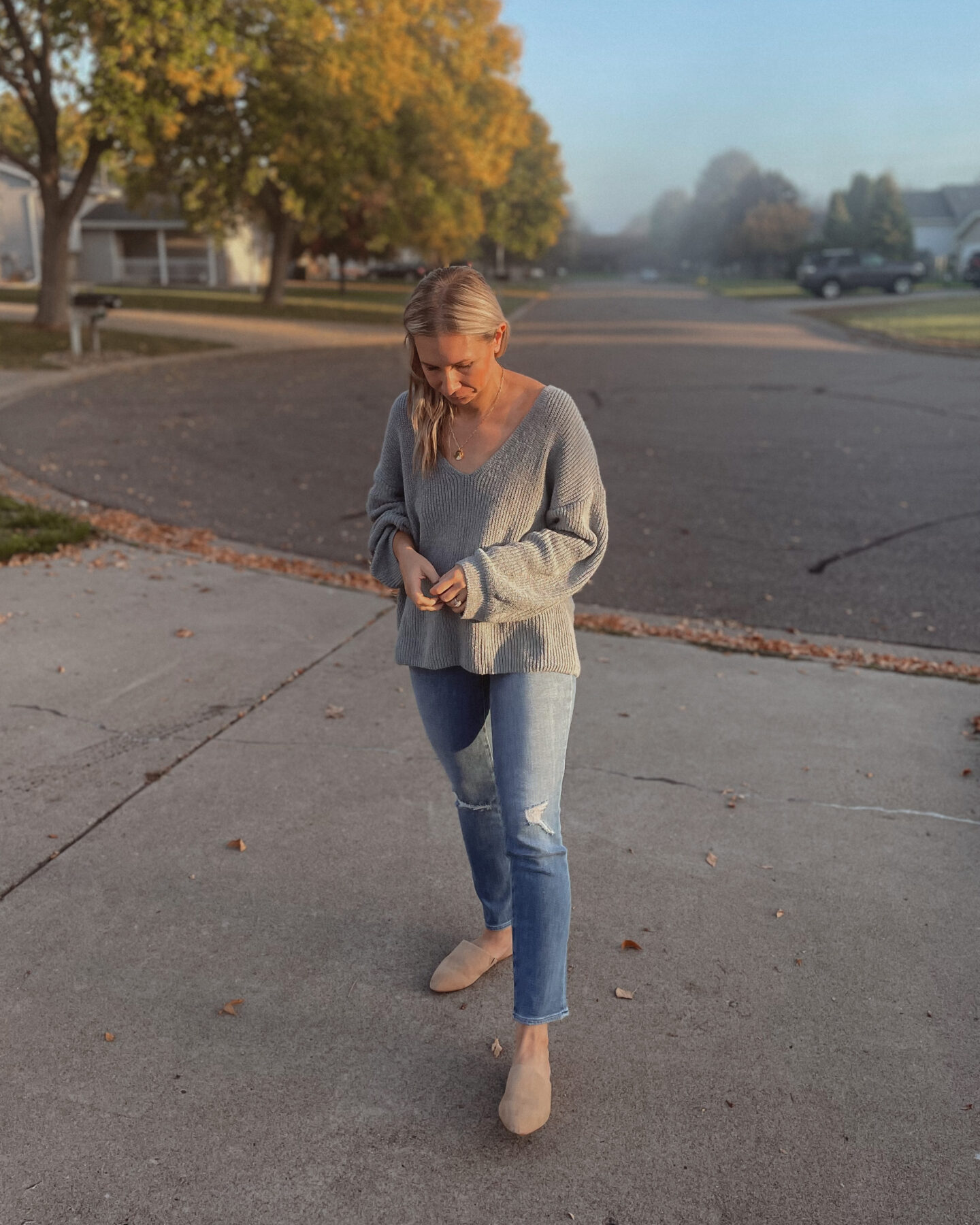 Karin Emily is wearing a blue sweater, distressed jeans, and Sherpa mules