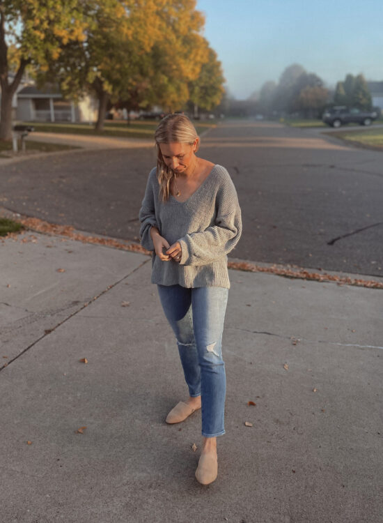 Karin Emily is wearing a blue sweater, distressed jeans, and Sherpa mules