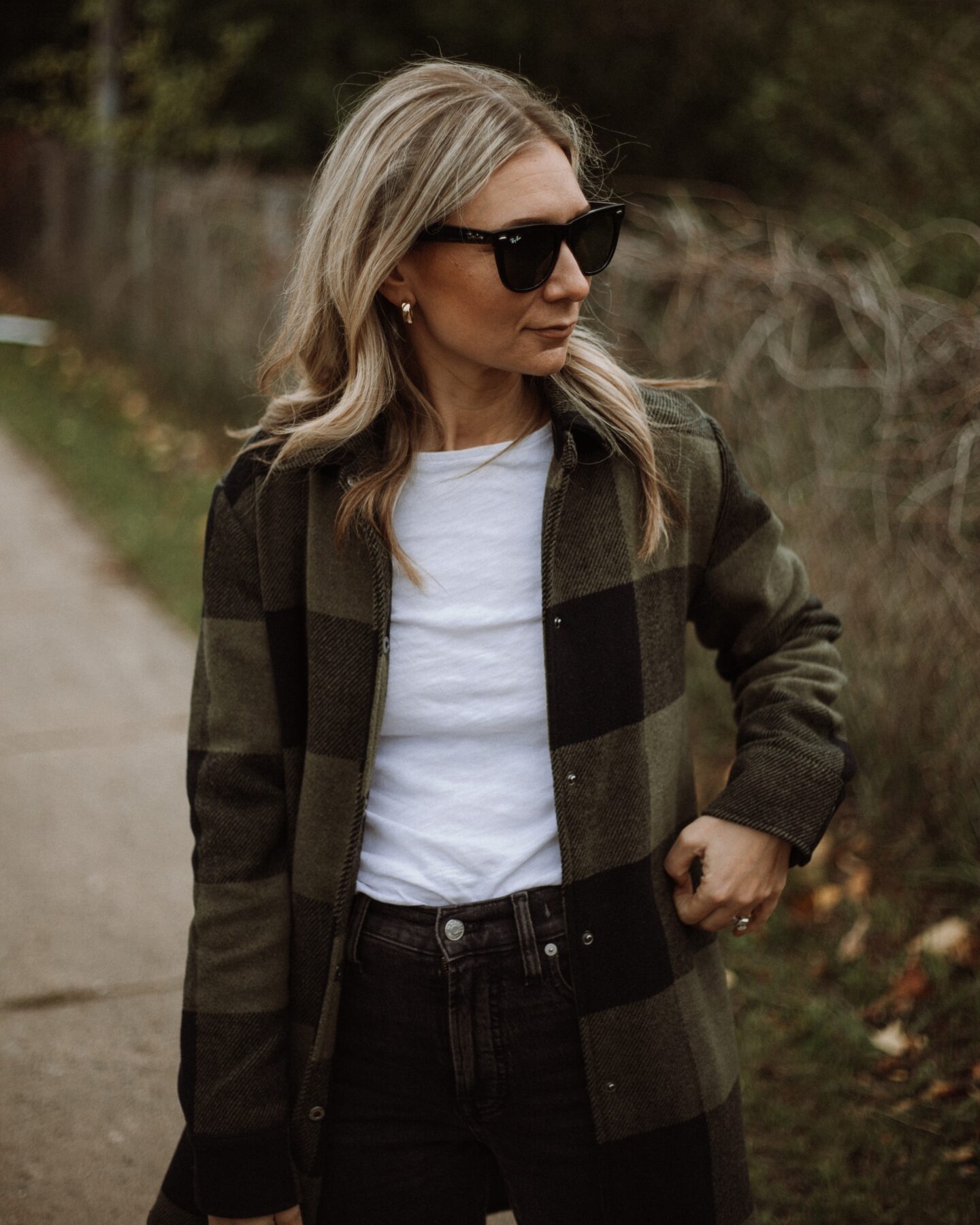 Karin Emily wears a white tee, plaid shacket, washed black perfect vintage jeans from Madewell and Veja V-10 Sneakers