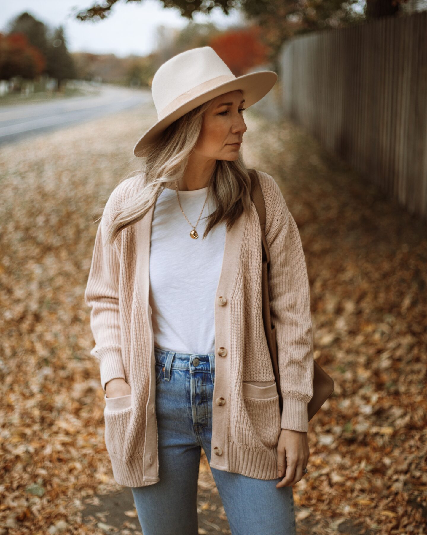 Karin Emily wears a pink cardigan, white tee, light wash levi wedgie icon jeans, and a wide brimmed hat