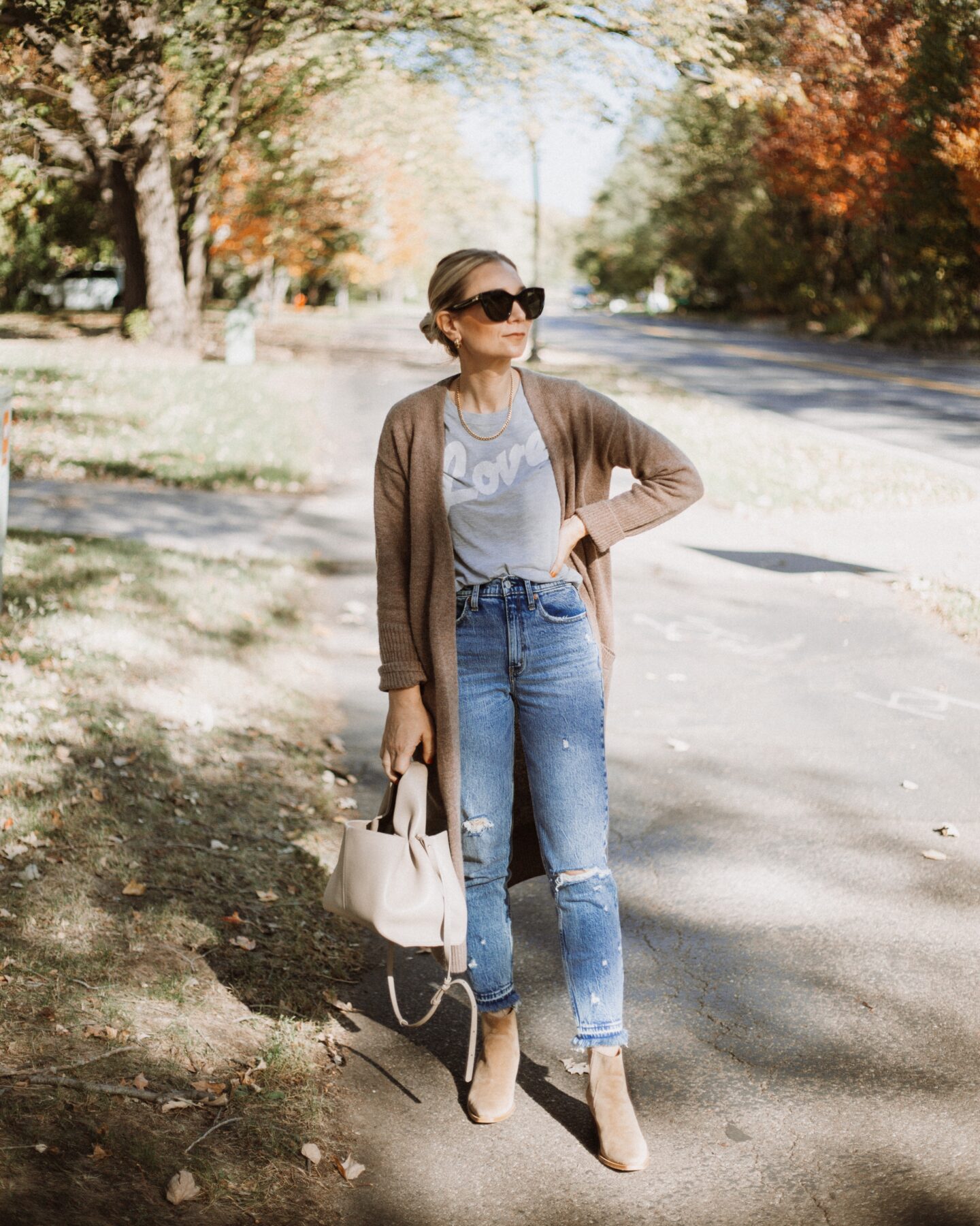 Karin Emily wears a graphic tee, cashmere cardigan, suede booties, and distressed jeans