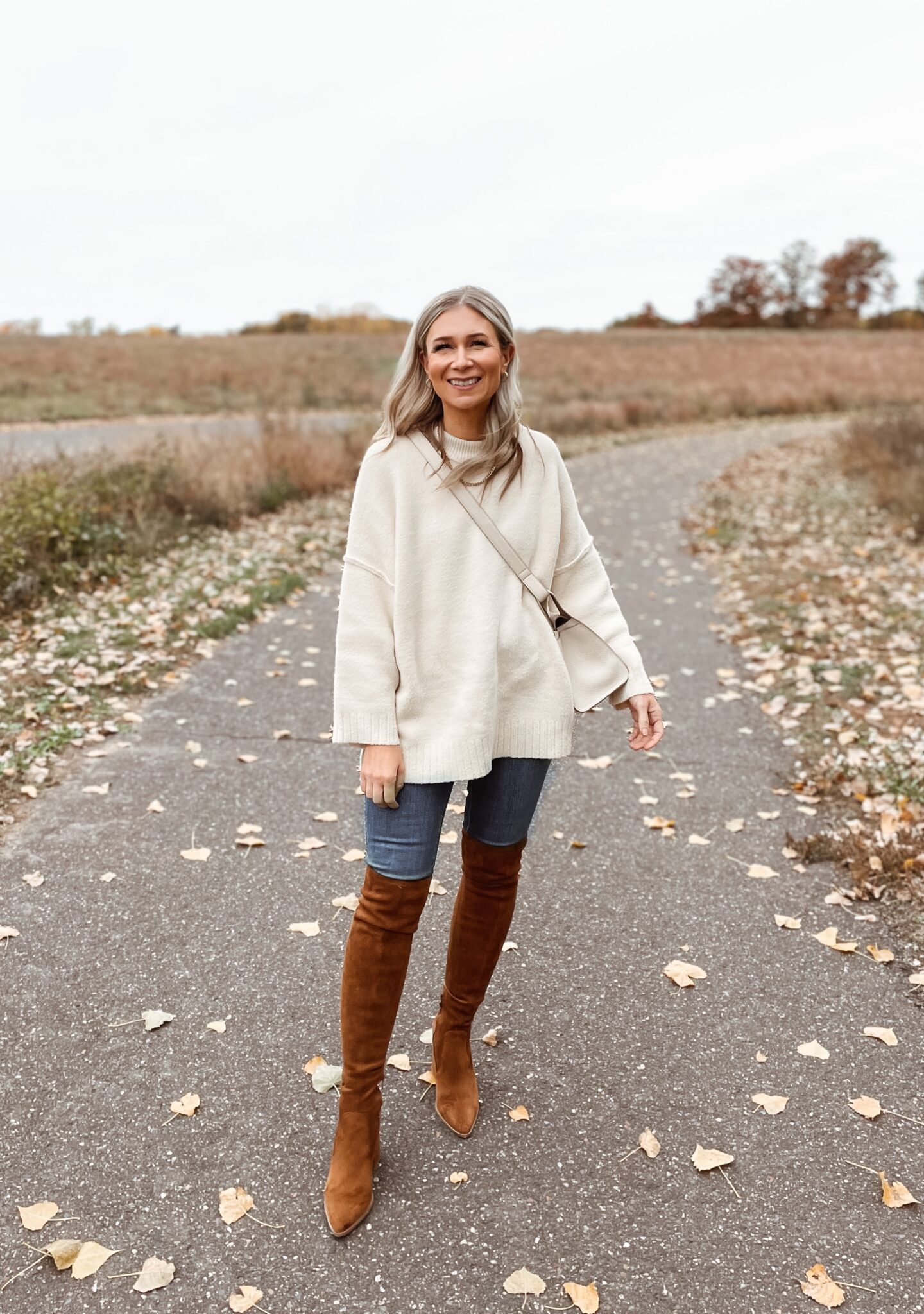 Karin Emily wears the Peaches sweater from Free People, dark wash skinny jeans, and brown over the knee boots