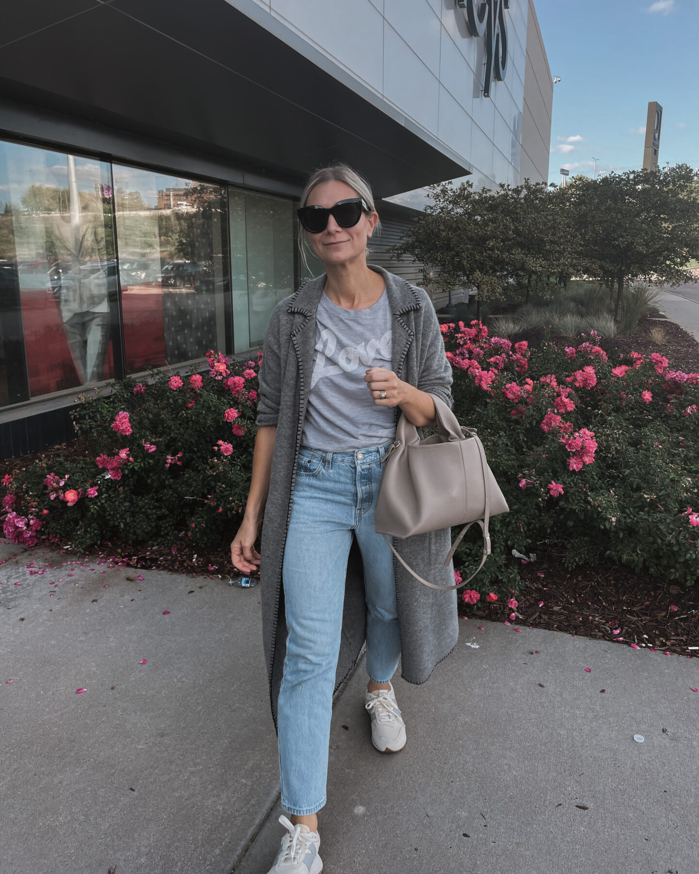 Karin Emily wears a fall maxi cardigan, graphic tee, light wash levi jeans and new balance sneakers