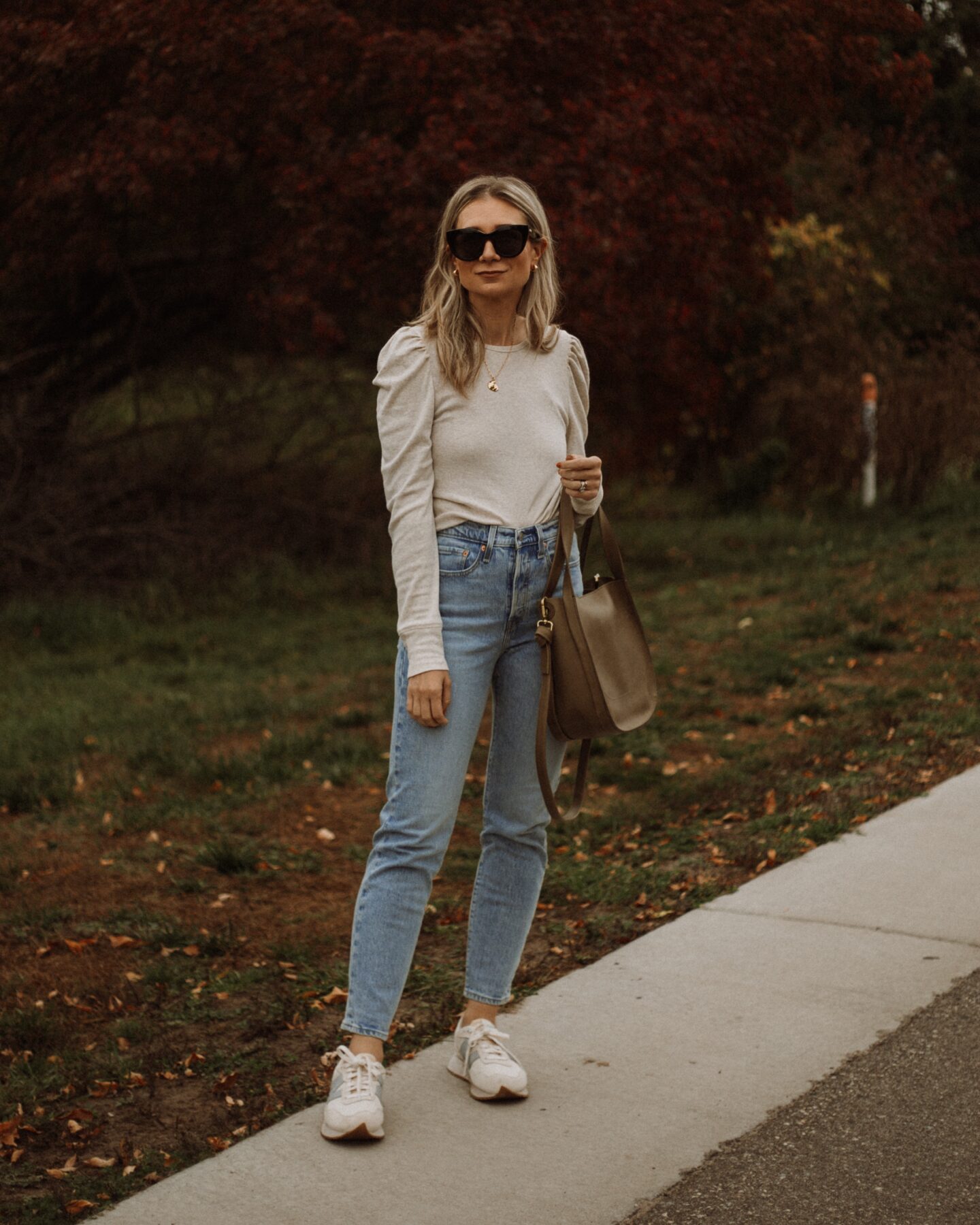 Karin Emily wear a puff sleeve top, light wash wedgie icon Levi jeans, new balance sneakers, and le specs black air heart sunglasses