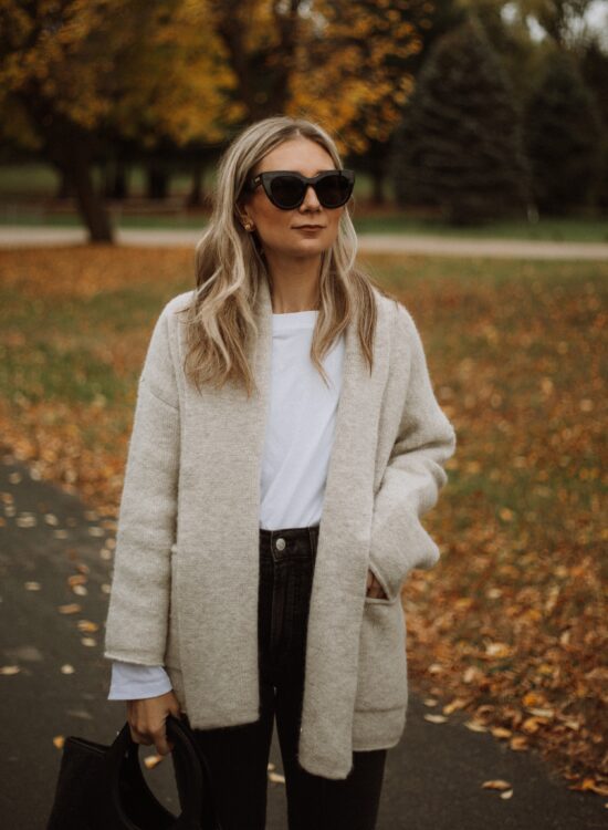 Karin Emily wears a Madewell shawl cardigan, white tee, black madewell perfect vintage jeans, and a wool Hereu bag,