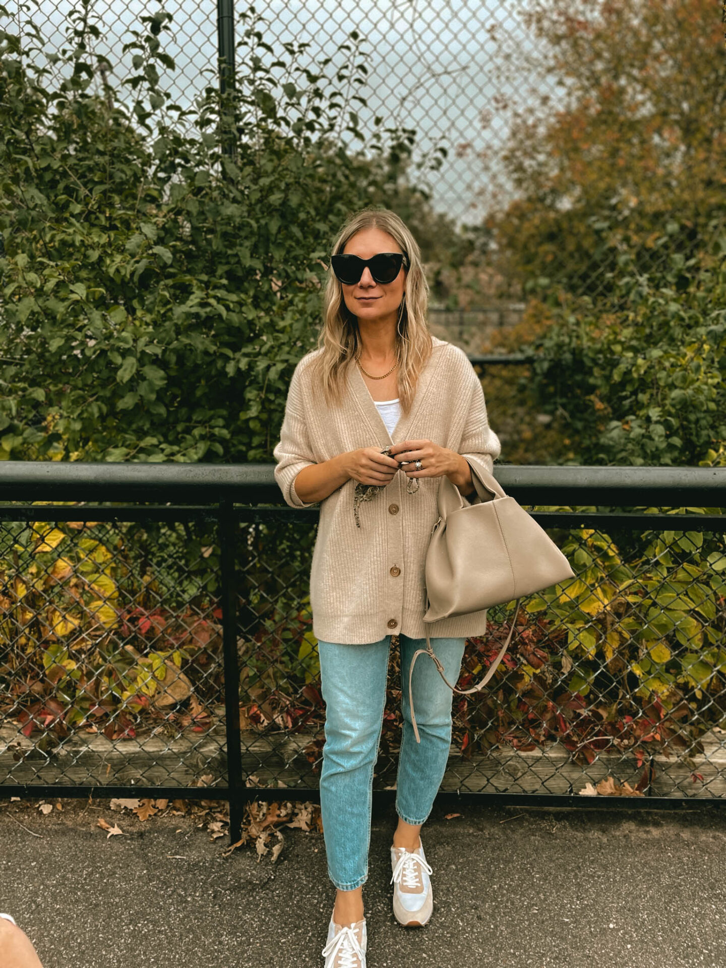 Karin Emily wears a Jenni Kayne Cashmere cocoon cardigan, light wash 90's cheeky jeans, and comfy sneakers