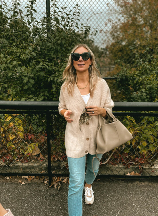 Karin Emily wears a Jenni Kayne Cashmere cocoon cardigan, light wash 90's cheeky jeans, and comfy sneakers