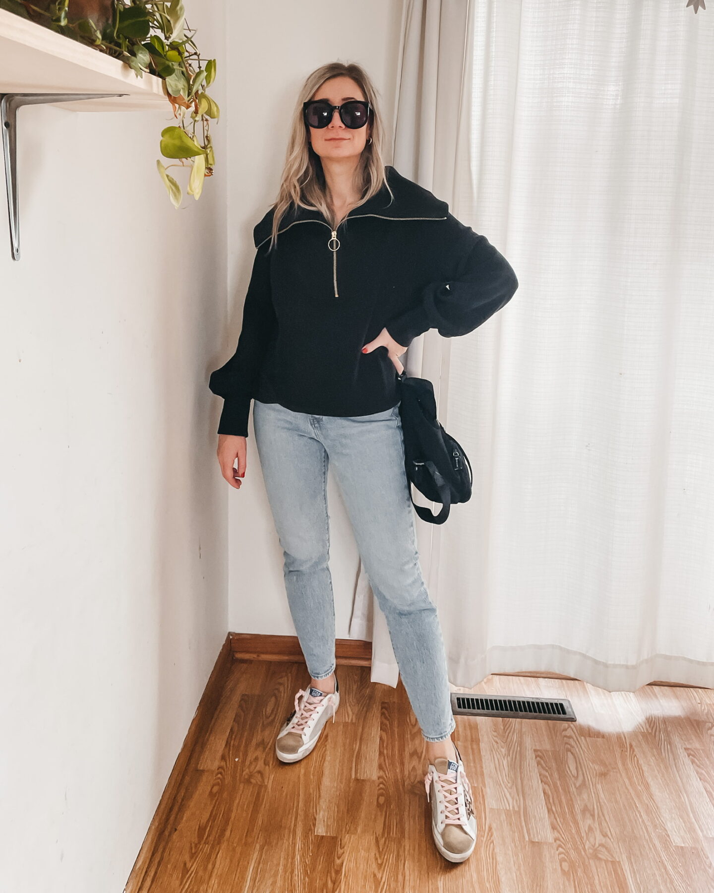 Karin Emily wears a Varley Half Zip Sweatshirt, Light Wash Jeans, and Golden Goose Sneakers