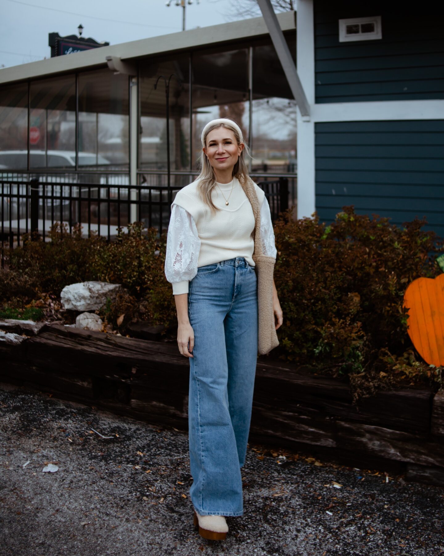 Karin Emily wears a puff sleeve sweater, wide leg jeans, and a pair of sherpa clogs