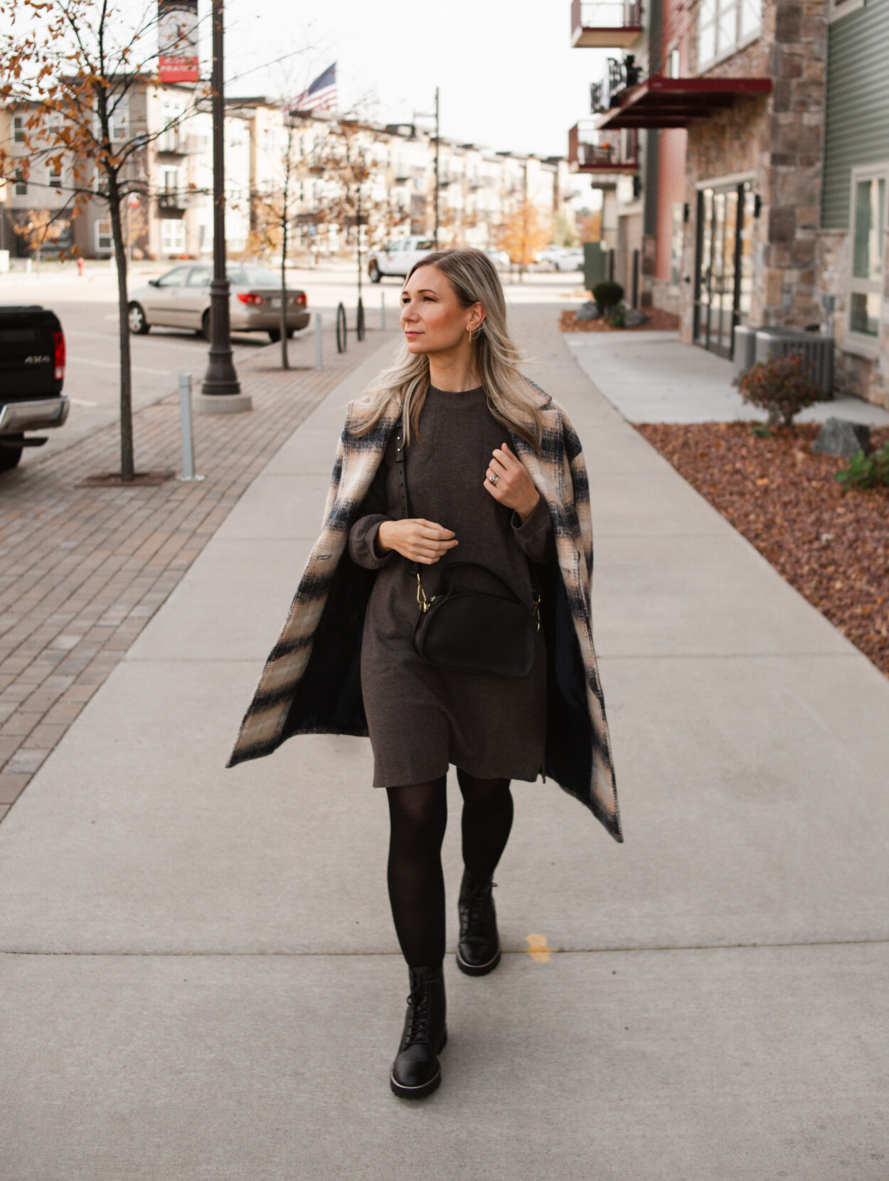 Karin Emily wears a plaid coat and charcoal sweater dress and black combat boots from Madewell