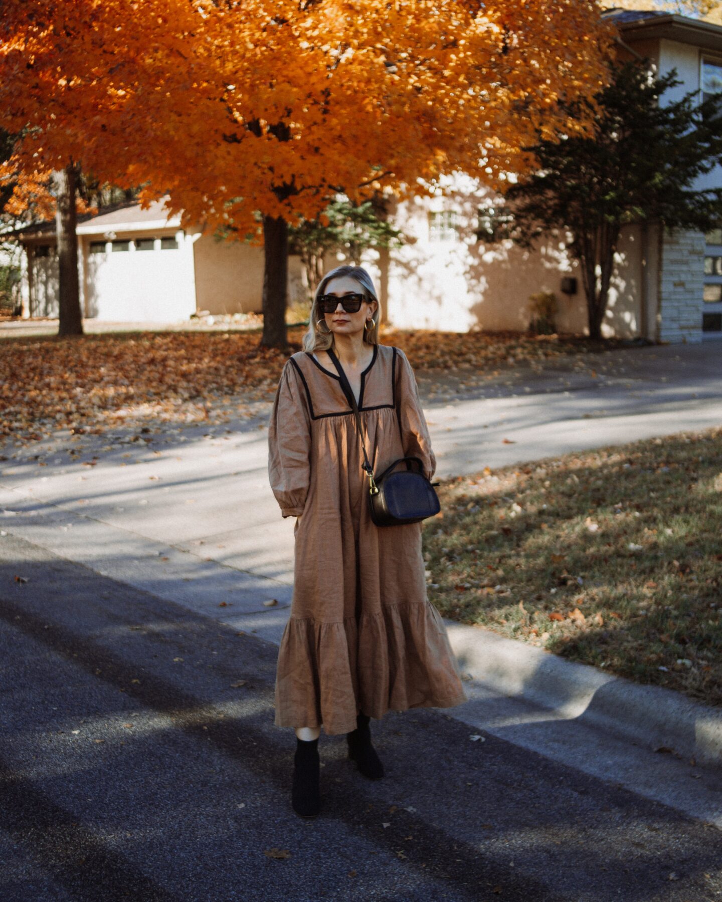 Karin Emily shares Thanksgiving outfit ideas and wears an ethically made linen dress from Sugar Candy Mountain, Black Sock Boots, and a Black shoulder bag from Madewell