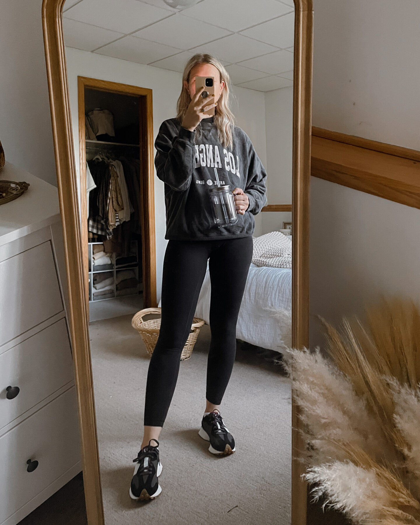 Karin Emily wears an anine bing los angeles sweatshirt, black leggings, and new balance sneakers