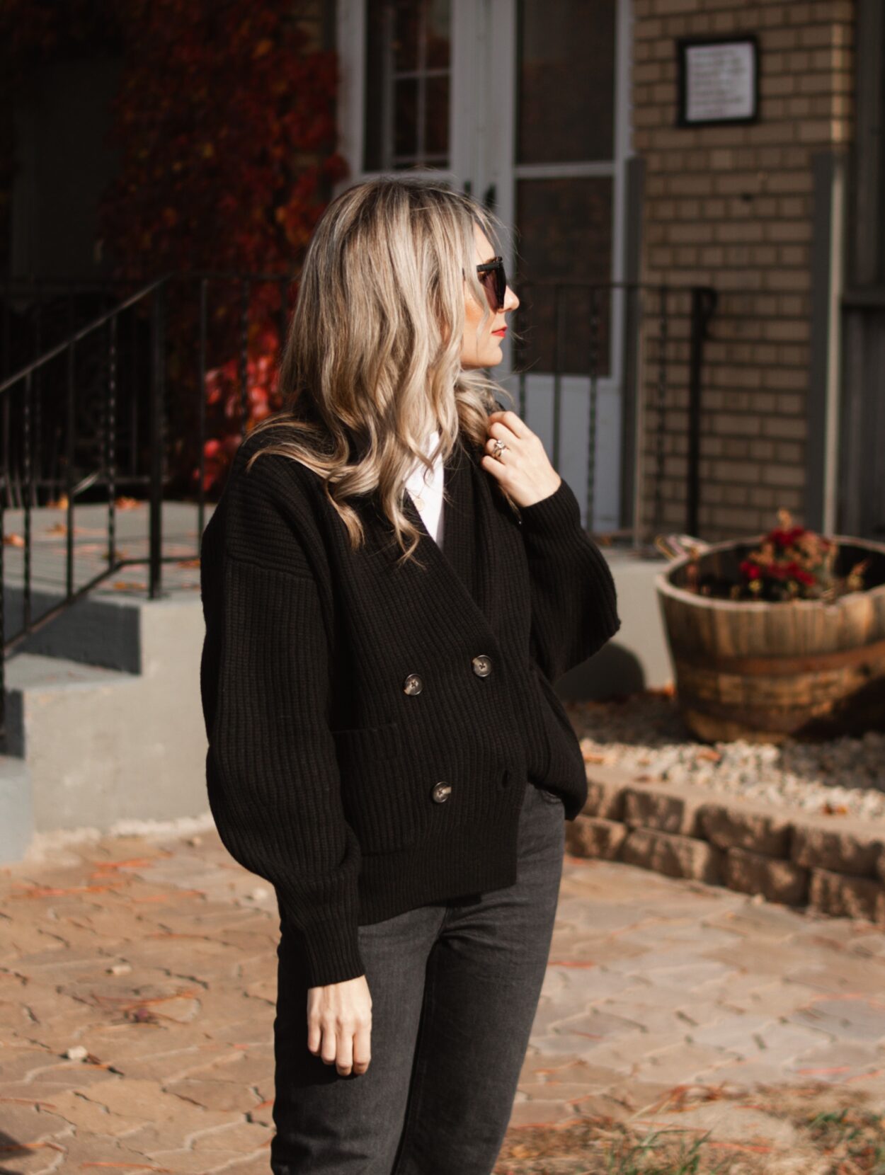 Karin Emily wears a casual holiday outfit with a black cardigan, white tee, black jeans, black boots, and a black bag all with new pieces from Everlane