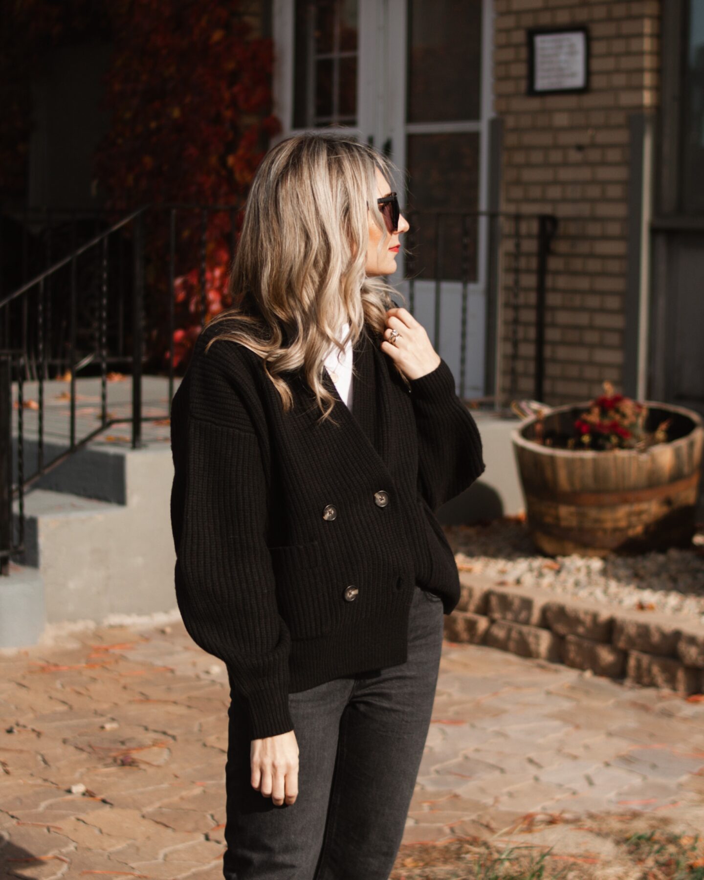 Karin Emily wears a casual holiday outfit with a black cardigan, white tee, black jeans, black boots, and a black bag all with new pieces from Everlane