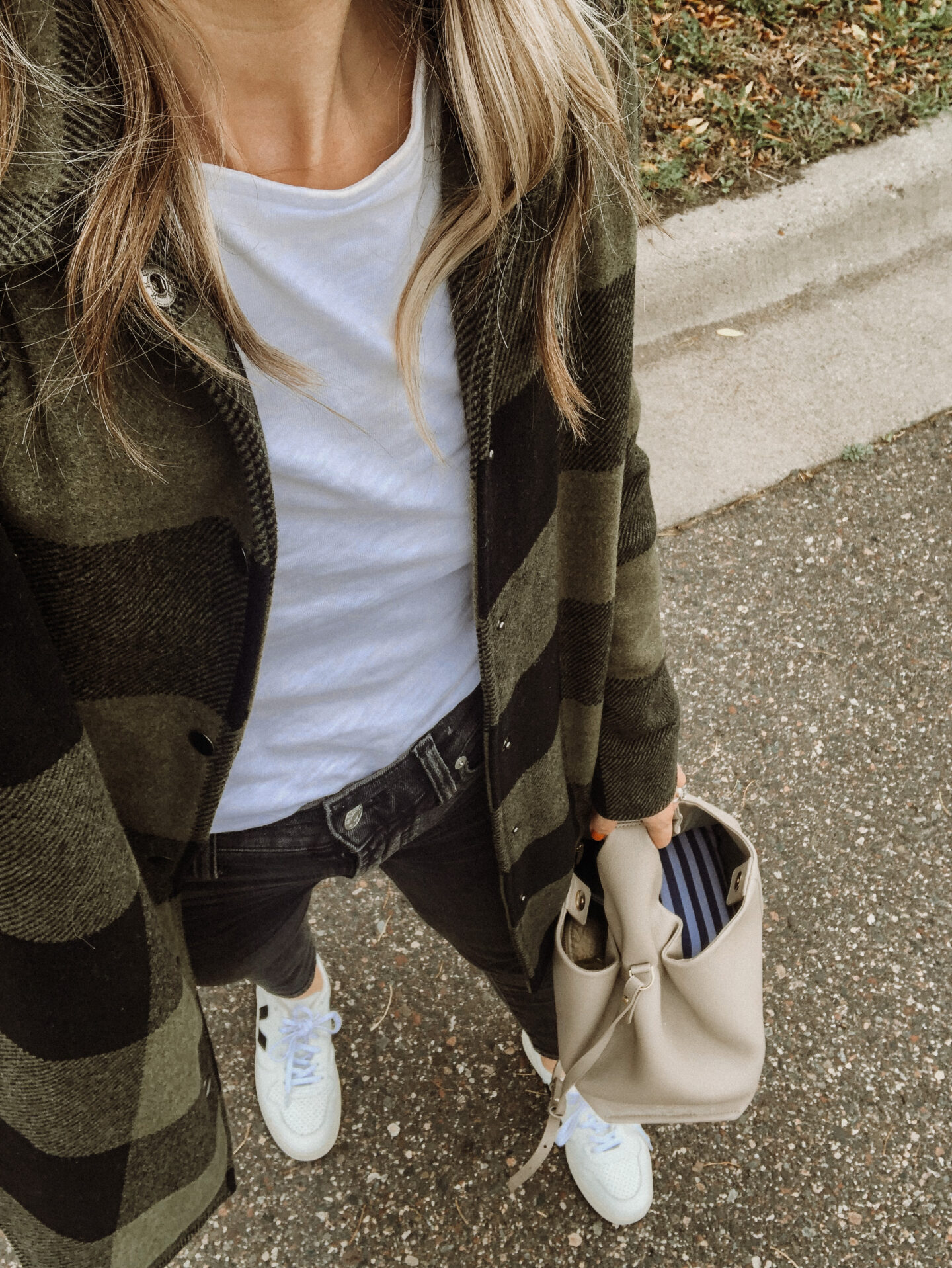 Karin Emily wears a buffalo check shacket, white tee, black jeans, and veja sneakers