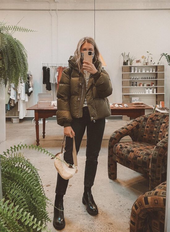 Karin Emily wears a green puffer coat, washed black 90's cheeky jeans from Everlane, and black lug boots