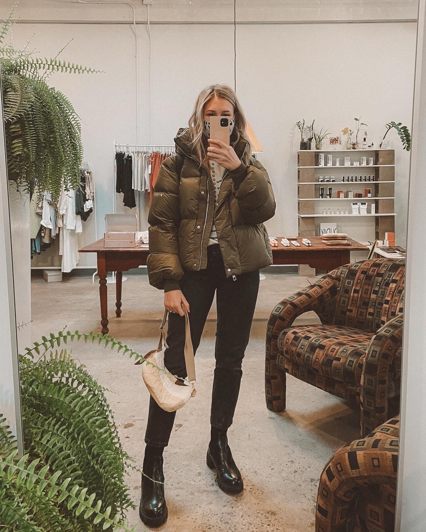 Karin Emily wears a green puffer coat, washed black 90's cheeky jeans from Everlane, and black lug boots