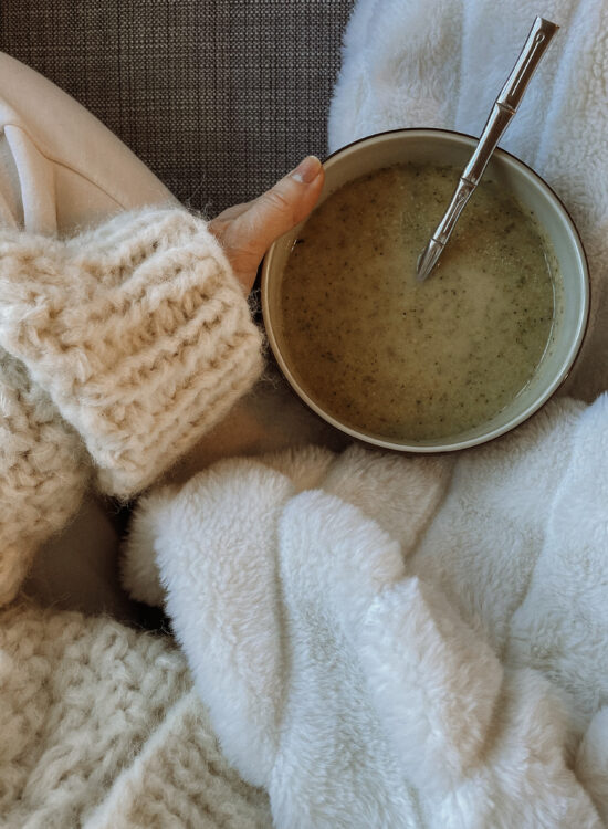 karin emily wears a chunky sweater, with a cuddly blanket and a bowl of soup