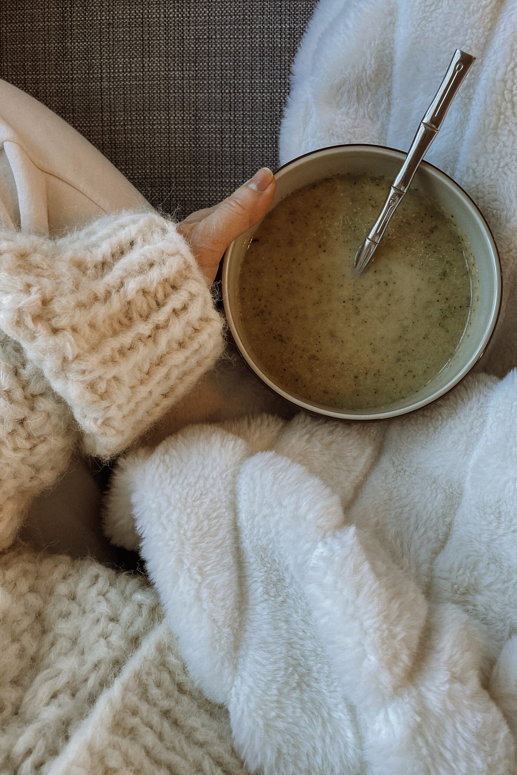 karin emily wears a chunky sweater, with a cuddly blanket and a bowl of soup